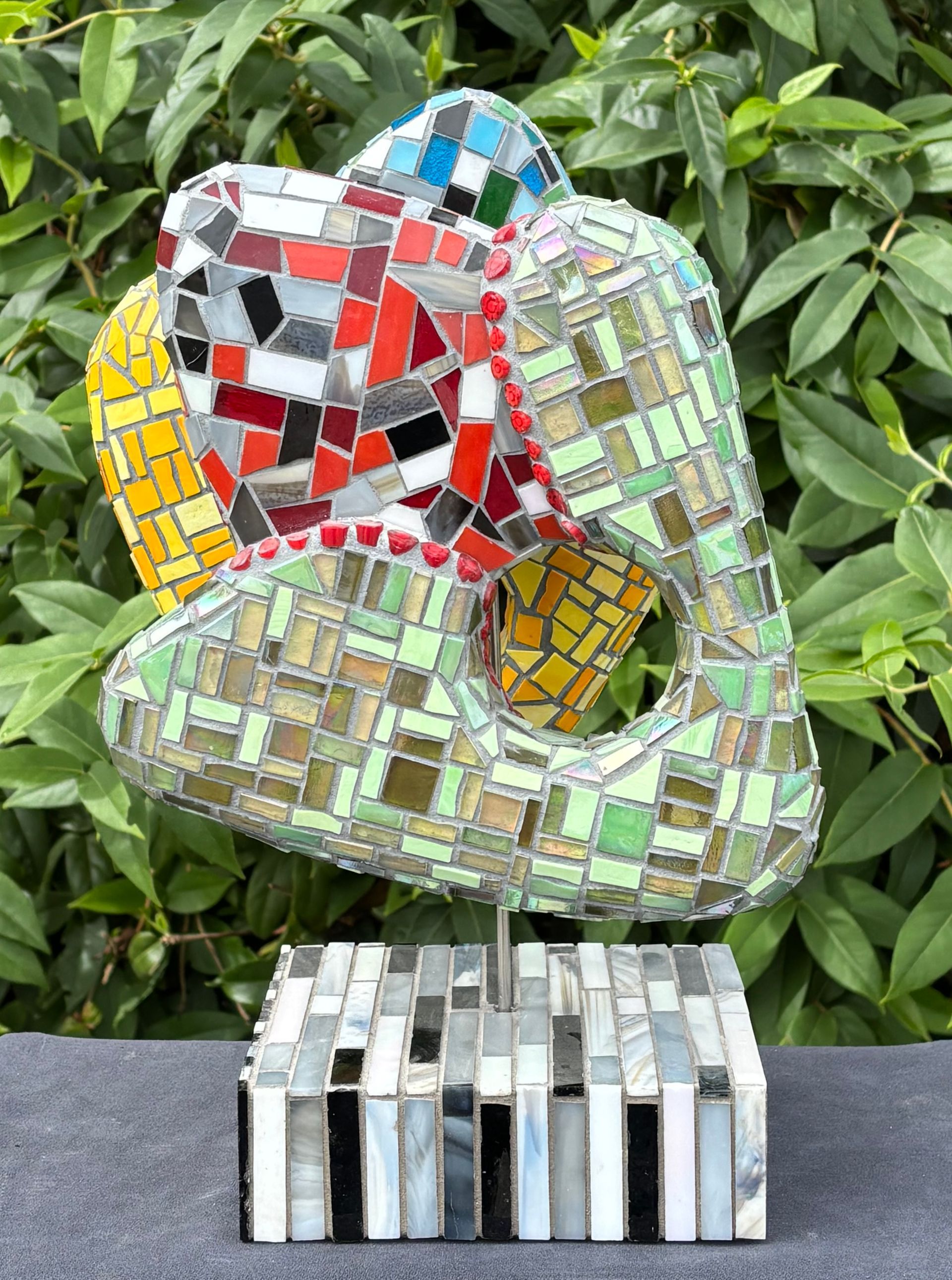 Een mozaïekbeeldhouwwerk staat op een zwarte sokkel