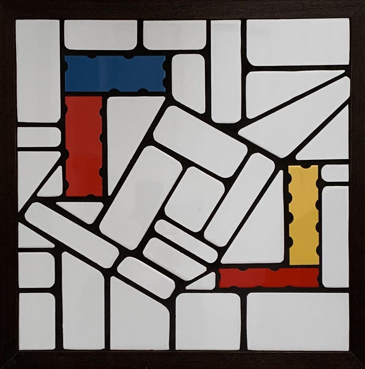 Een ingelijst tegelmozaïek met rood-gele en blauwe rechthoeken