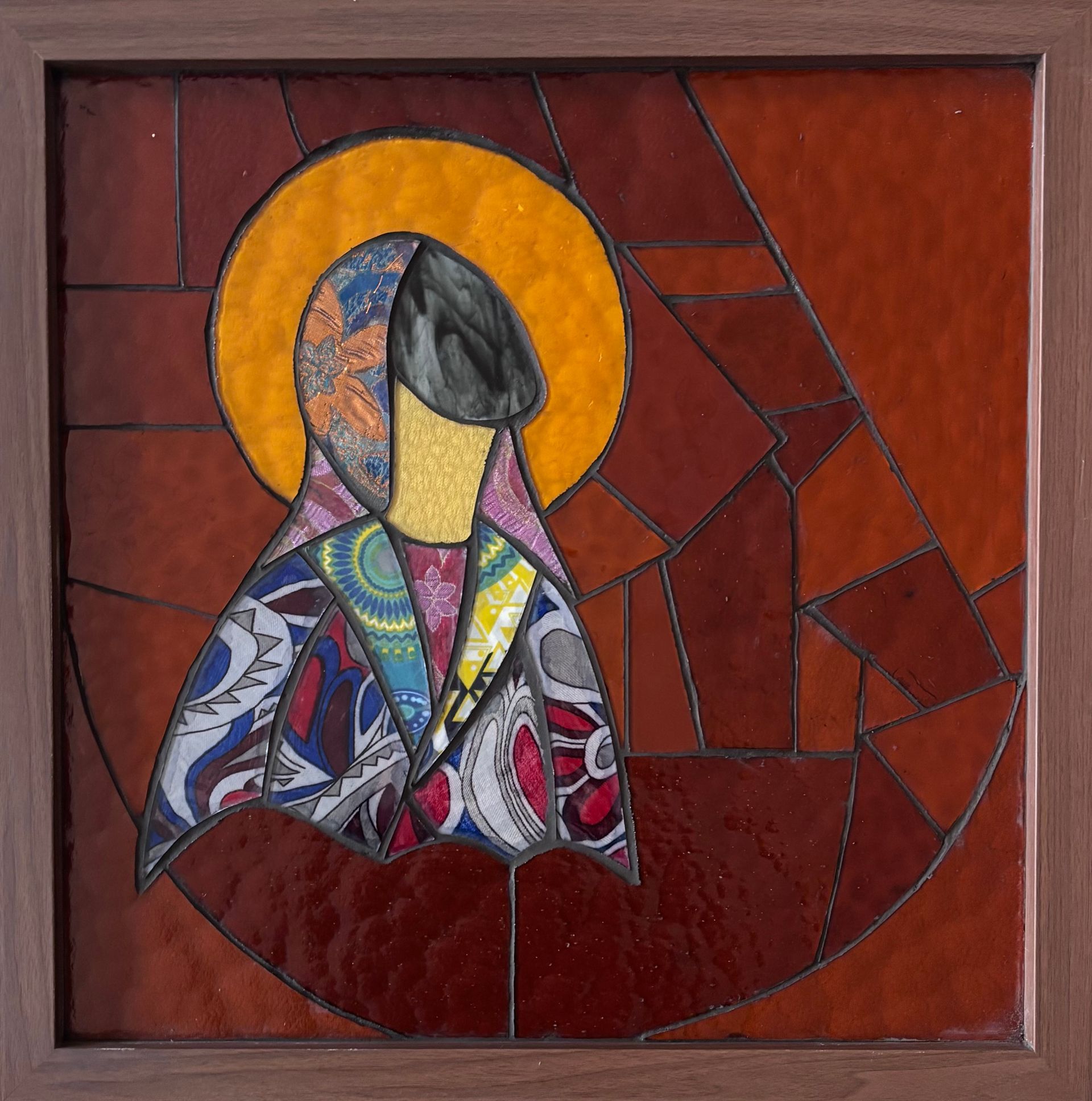 Kunstwerk van een Mariaf iguur met een aureool, gekleed in een stof met een patroon.