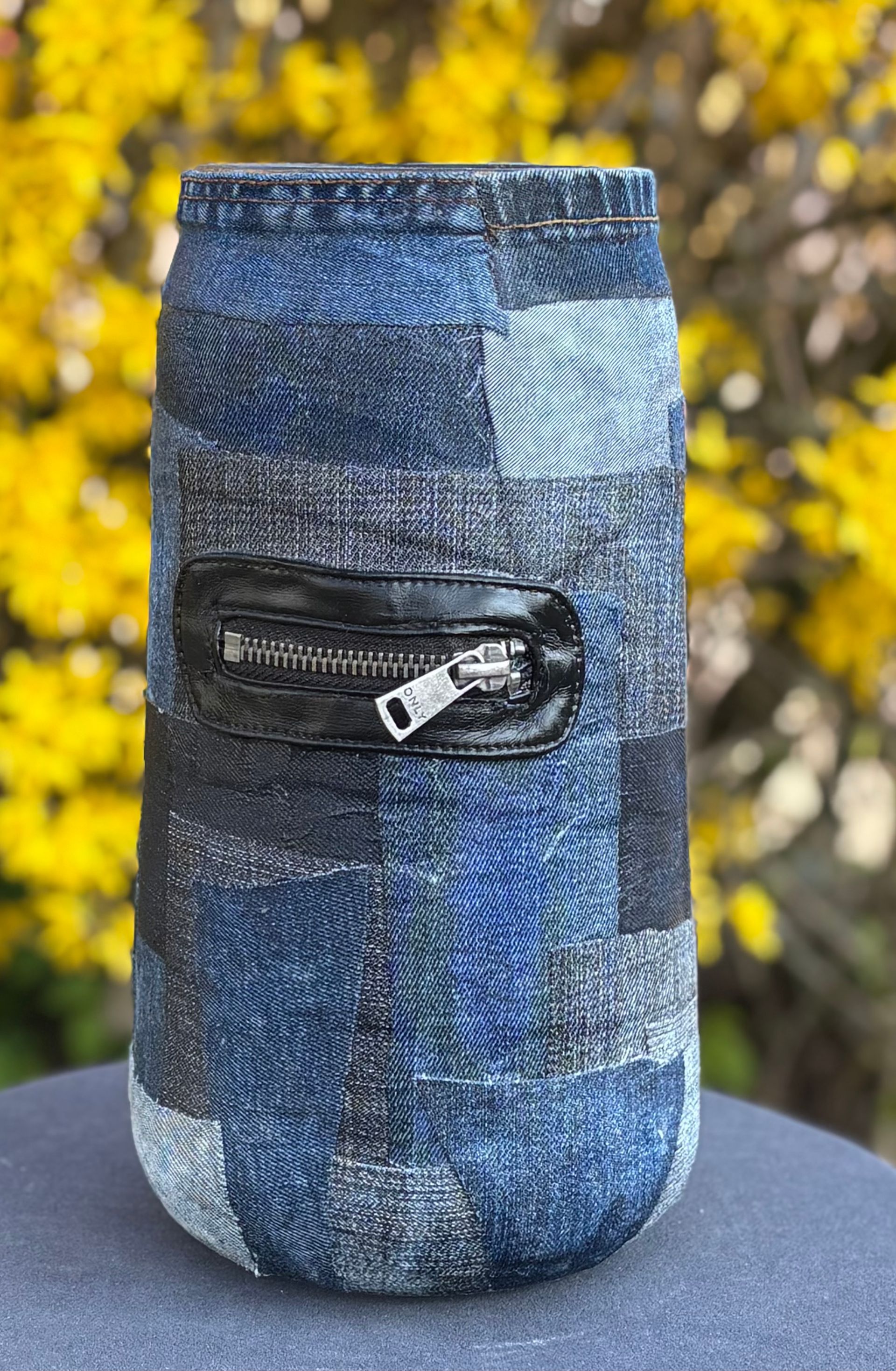 Ronde halskettinghanger met turquoise, iriserende stukjes abalone schelp aan een zwart koord, op een houten ondergrond.