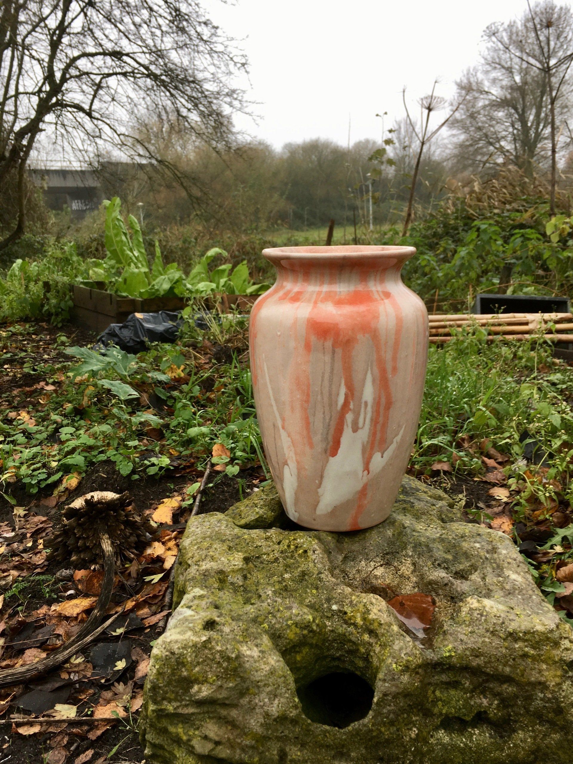 Een vaas staat op een rots in een tuin.