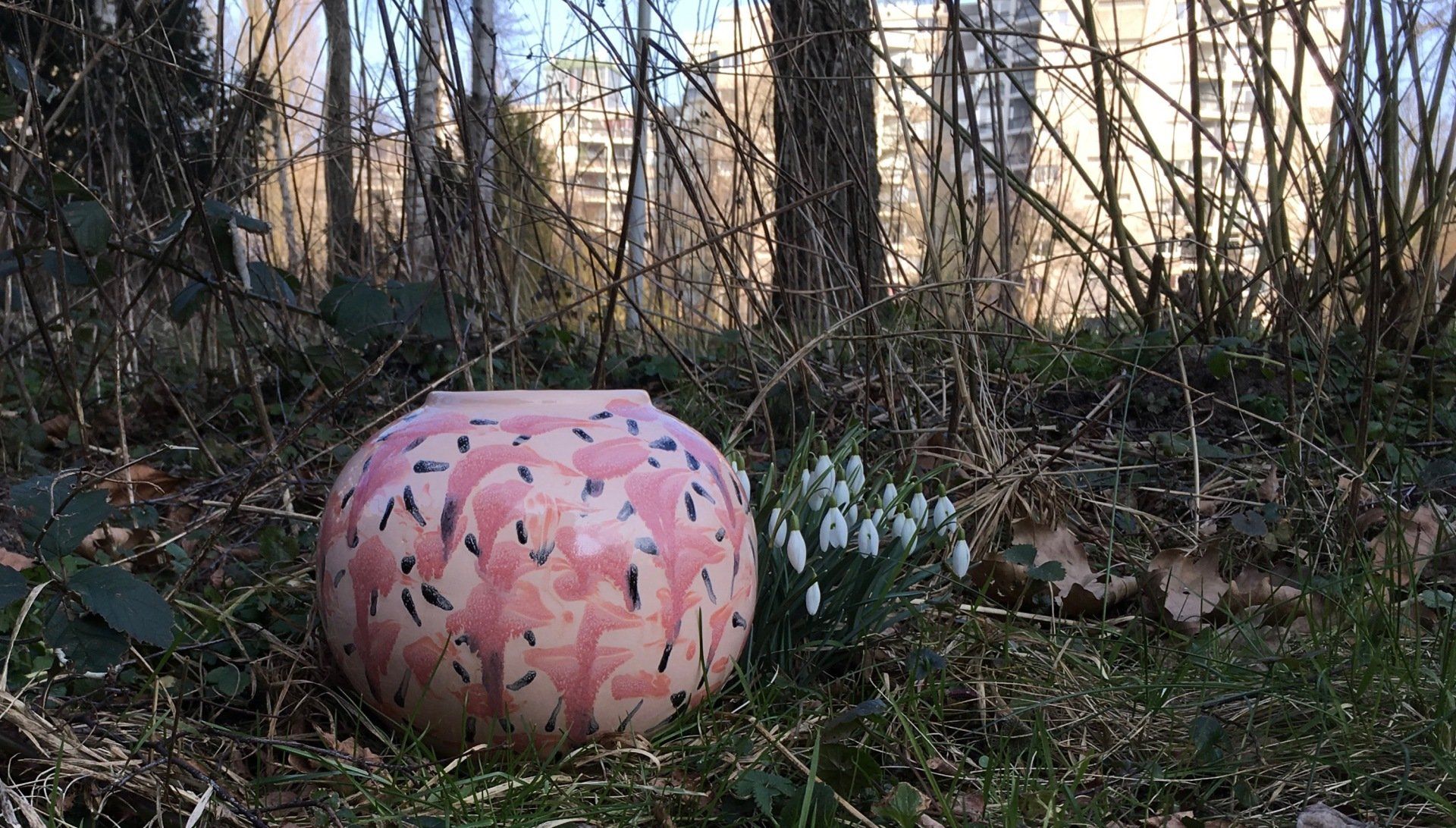 Een roze vaas staat midden in een bos.