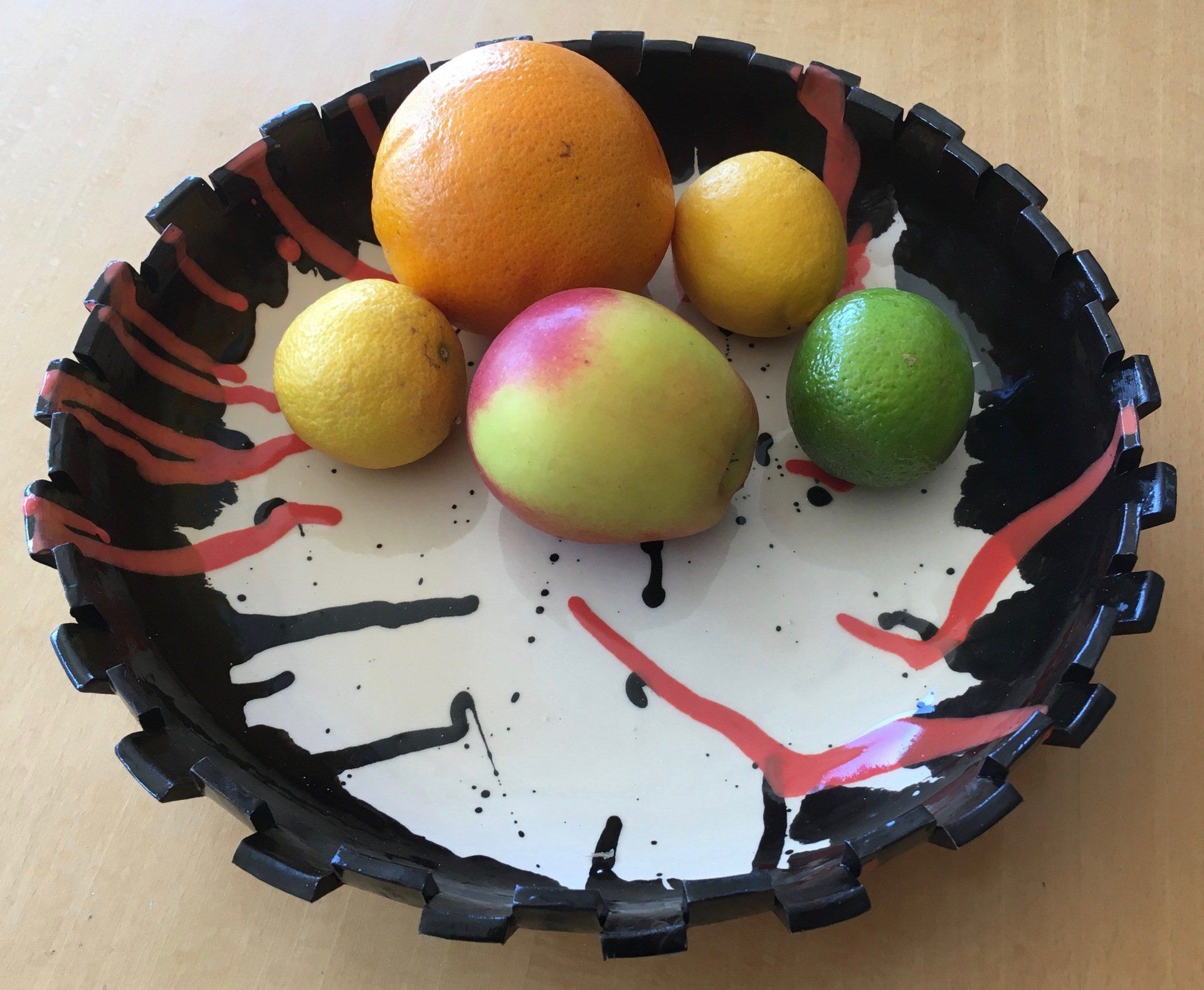 Een zwart-witte kom gevuld met fruit op een tafel