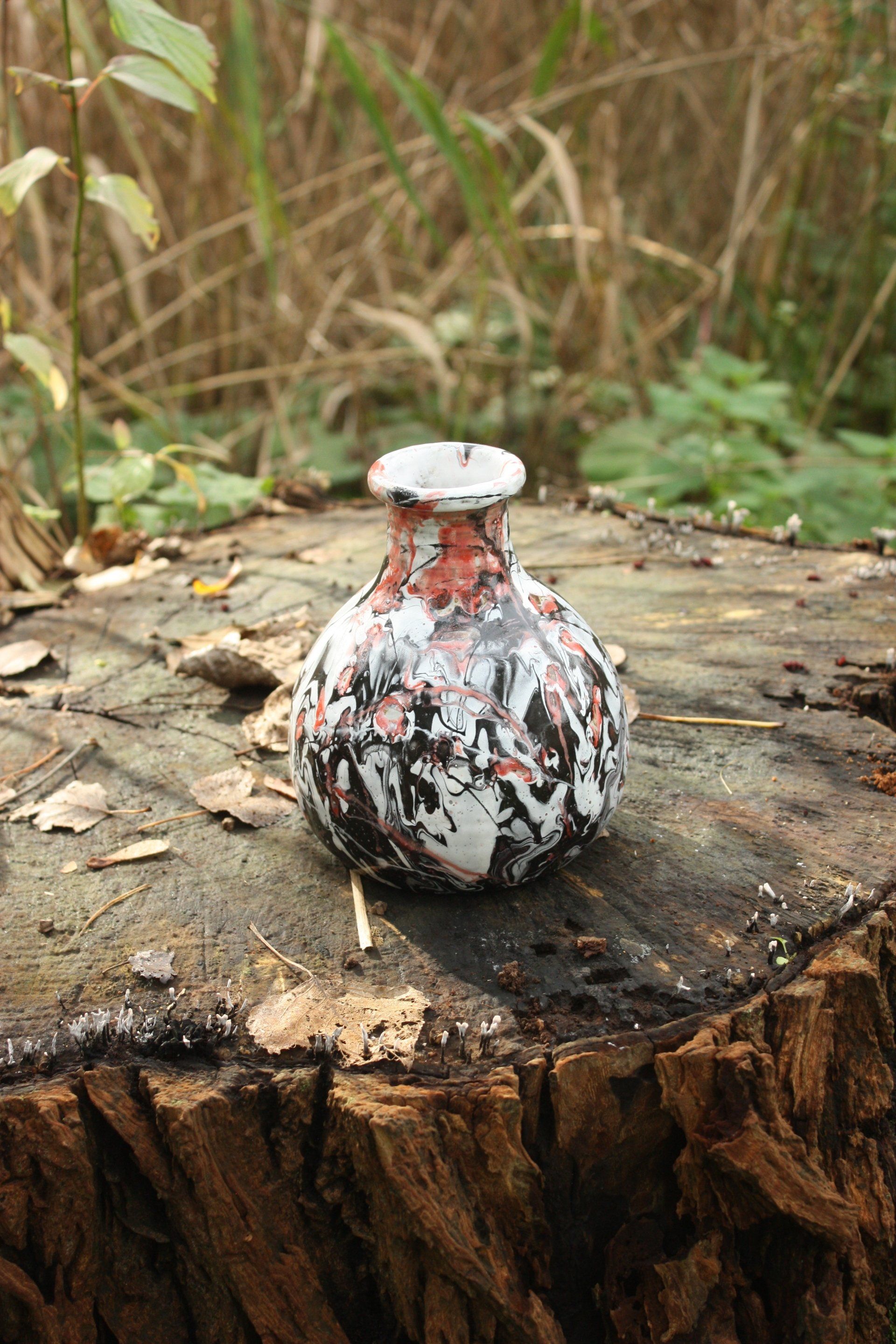 Een kleine vaas staat op een boomstronk.