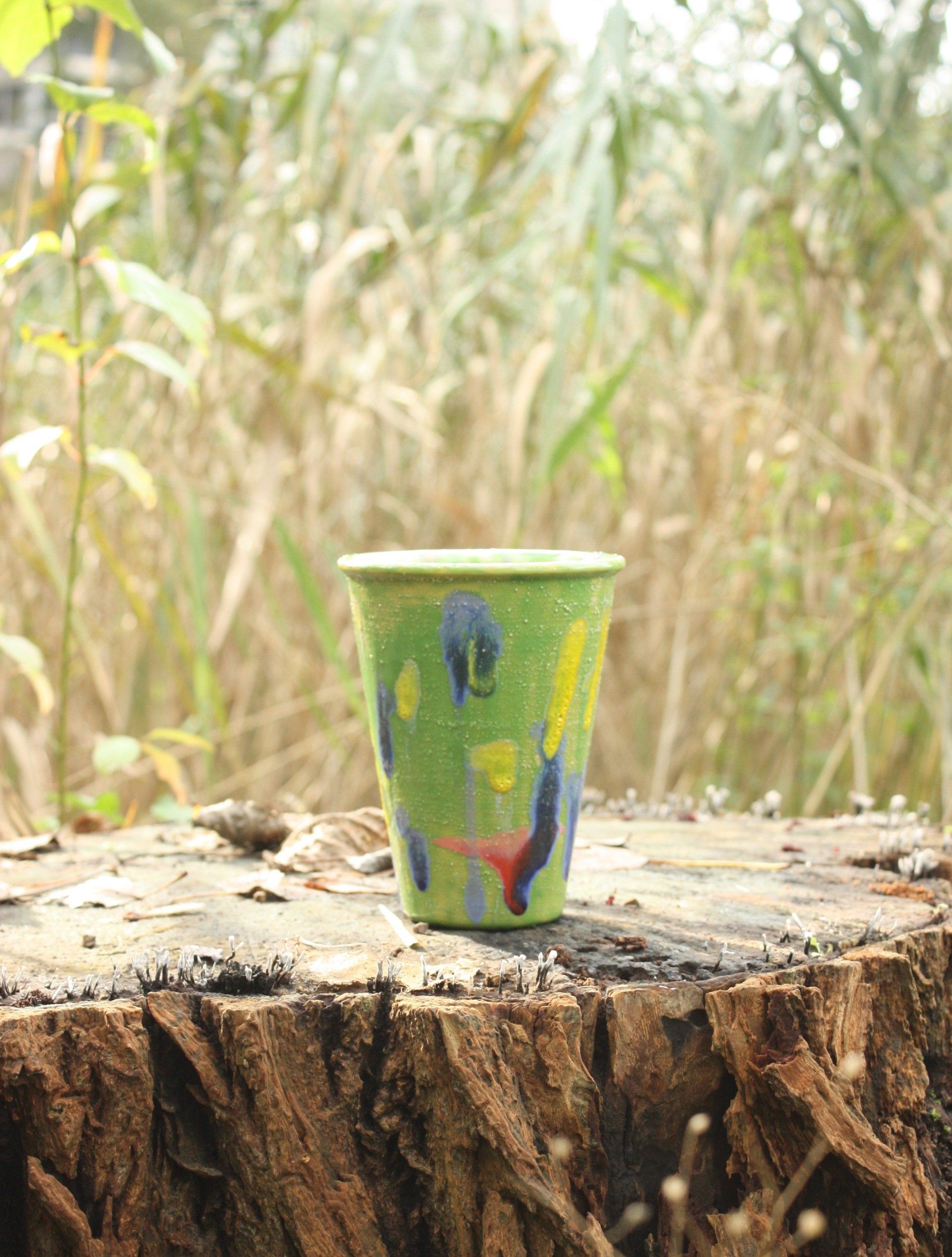 Een groene beker staat bovenop een boomstronk.