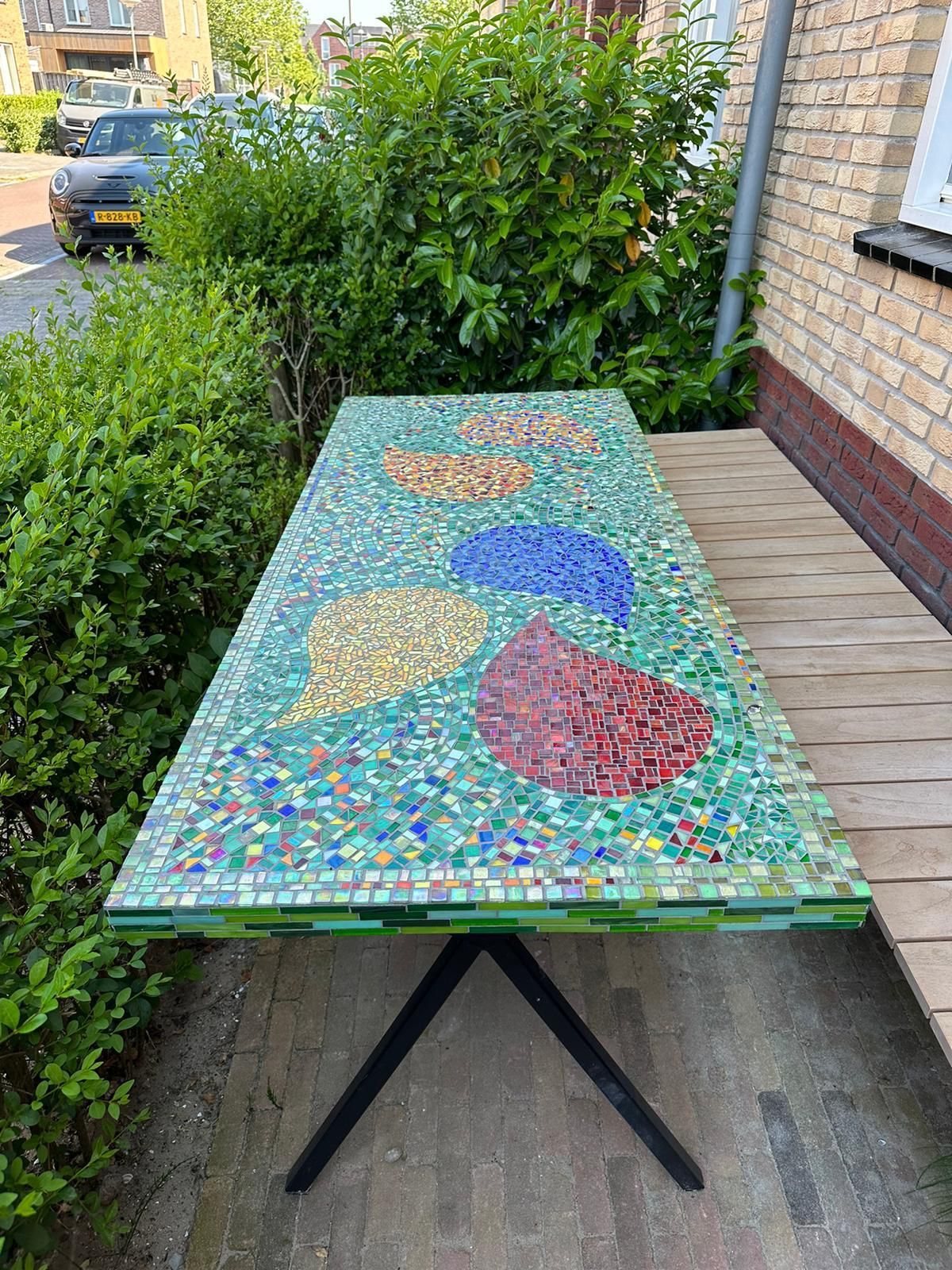 Voor eenhuis staat een kleurrijke mozaïektafel.