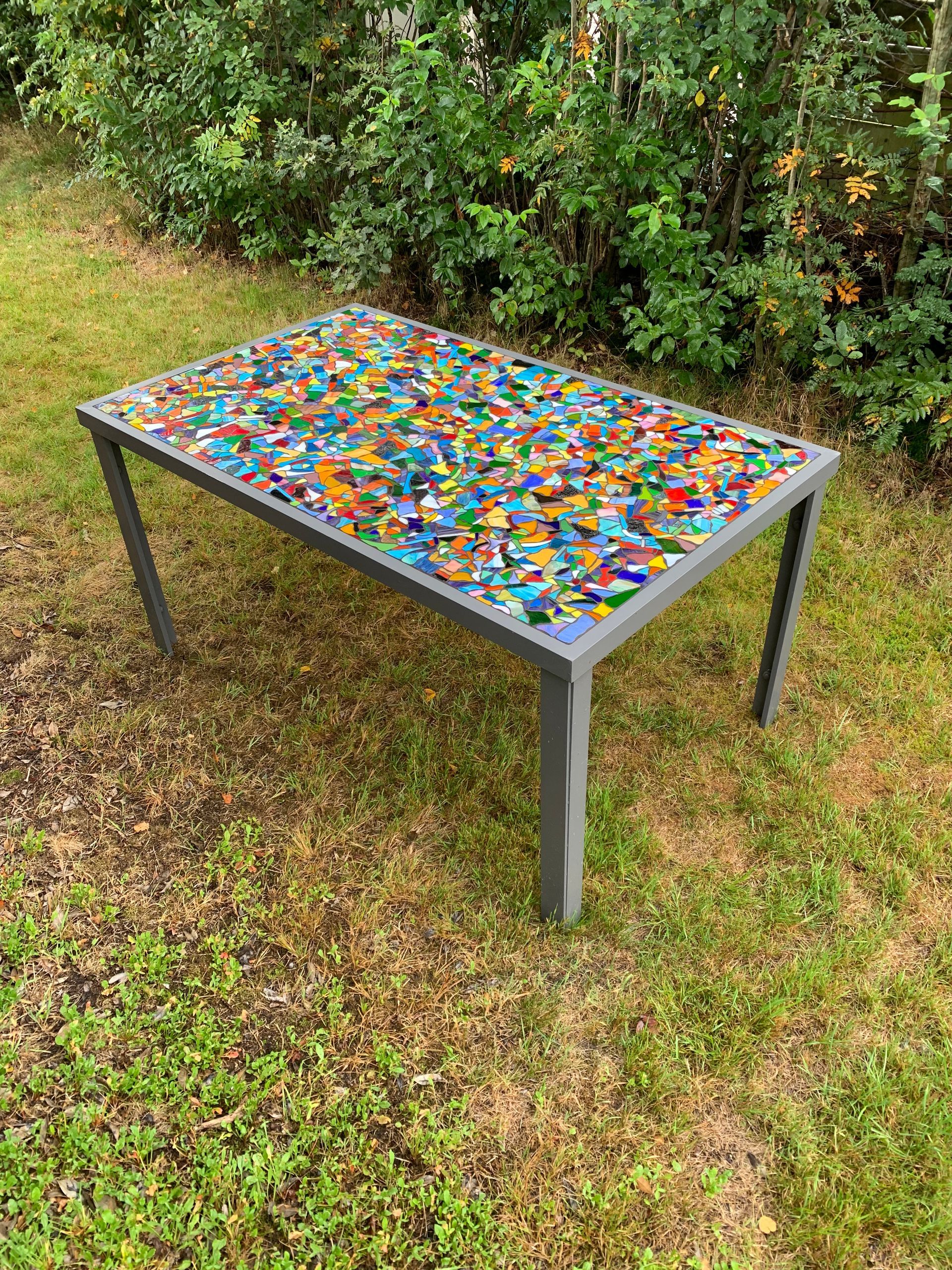 Een kleurrijke salontafel staat op een weelderig groen veld.