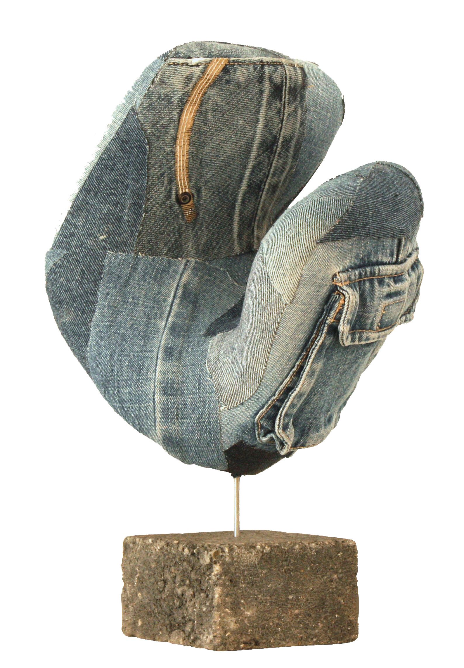 Een abstracte sculptuur gemaakt van blauwe denimstofresten, gemonteerd op een dunne staaf en een vierkante, ruw bewerkte stenen sokkel.