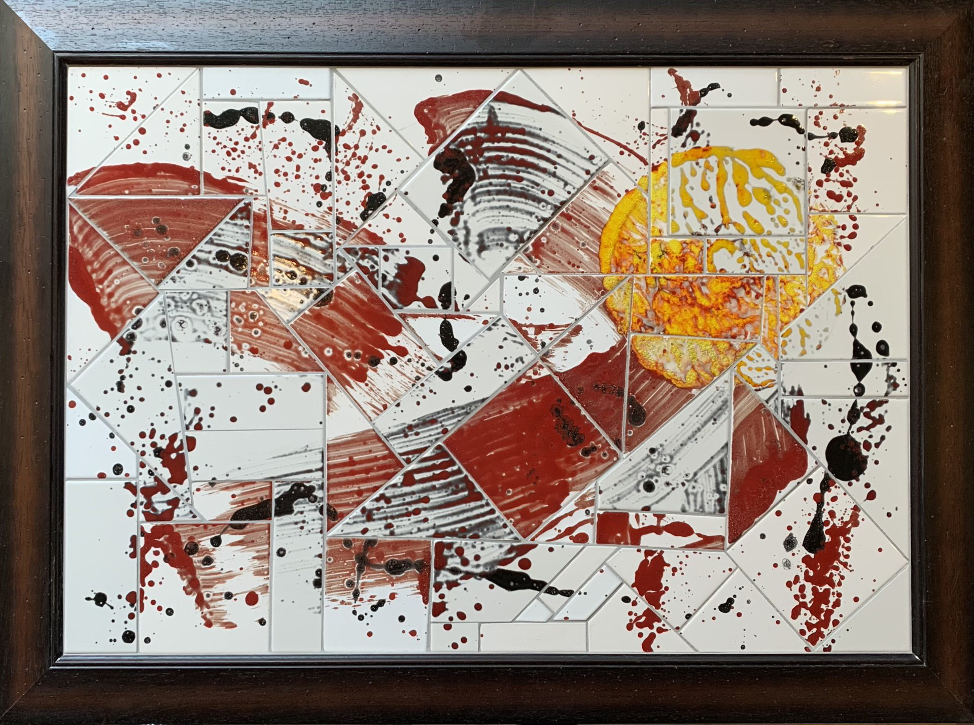 Een tegelmozaïek in een houten lijst met een gele cirkel in het midden