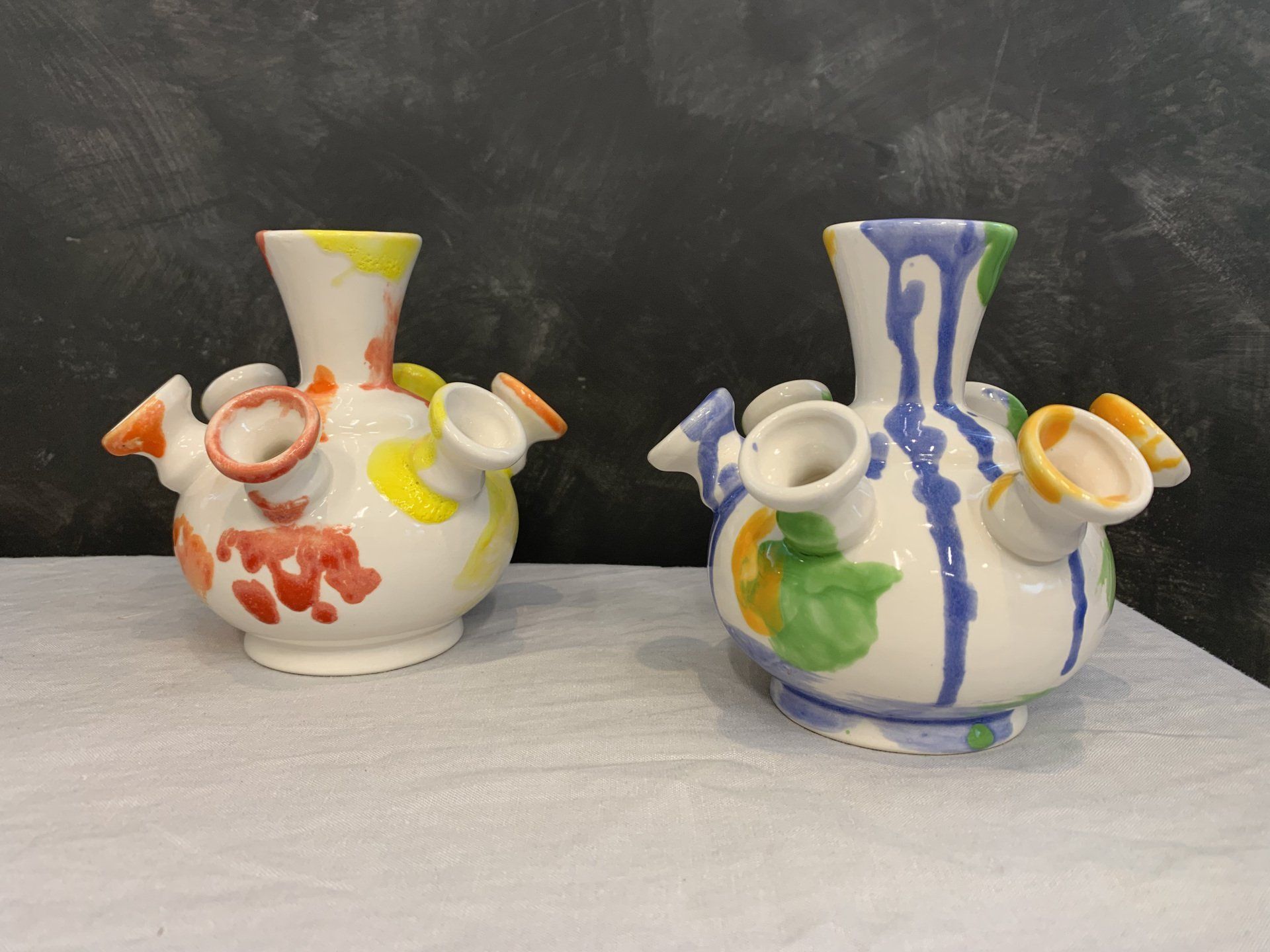 Twee kleurrijke vazen ​​staan ​​naast elkaar op een tafel.