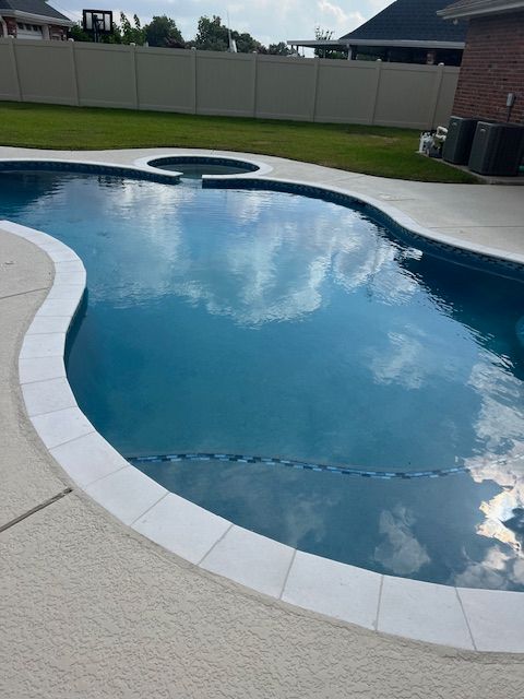 A person in overalls testing pool water with a handheld device near a house.