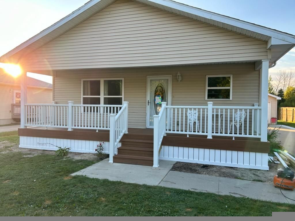A small house with a large porch and stairs.