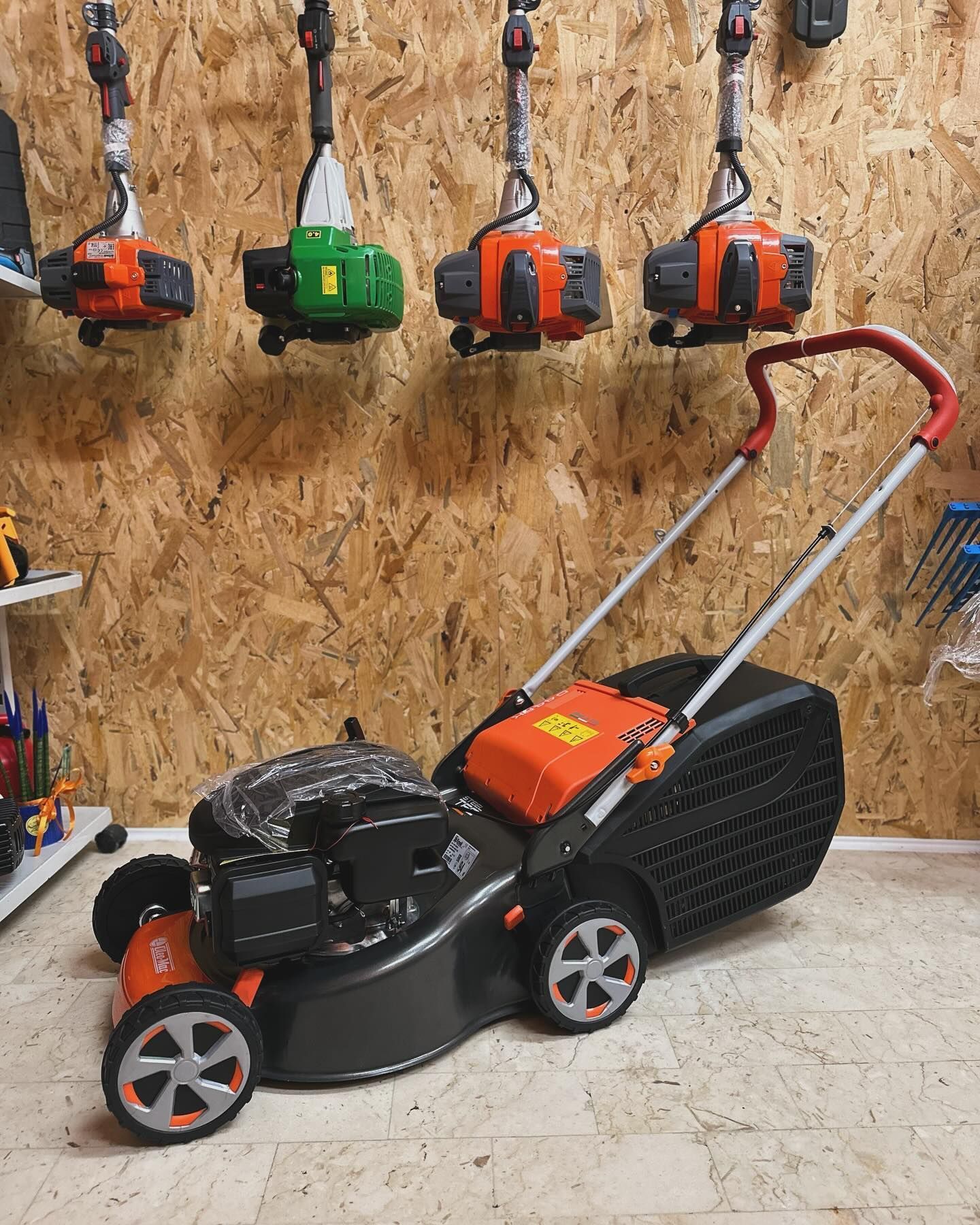 Un tosaerba è parcheggiato in un garage davanti a un muro di legno.
