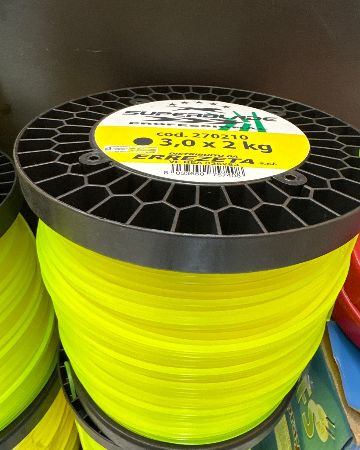 Diverse bobine di filo giallo per decespugliatore sono impilate una sopra l'altra