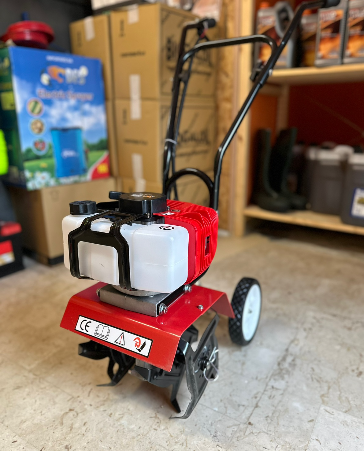 Un piccolo tosaerba rosso è appoggiato sul pavimento di un garage.