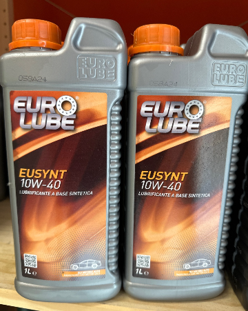 Due bottiglie di lubrificante europeo sono appoggiate su uno scaffale.