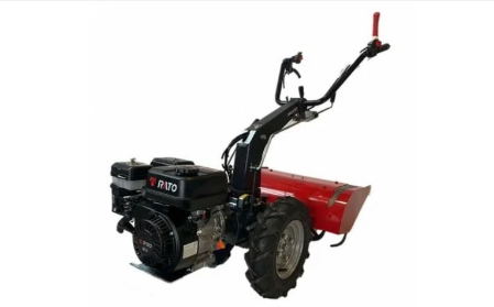 Un piccolo trattore con un aratro rosso attaccato su uno sfondo bianco.