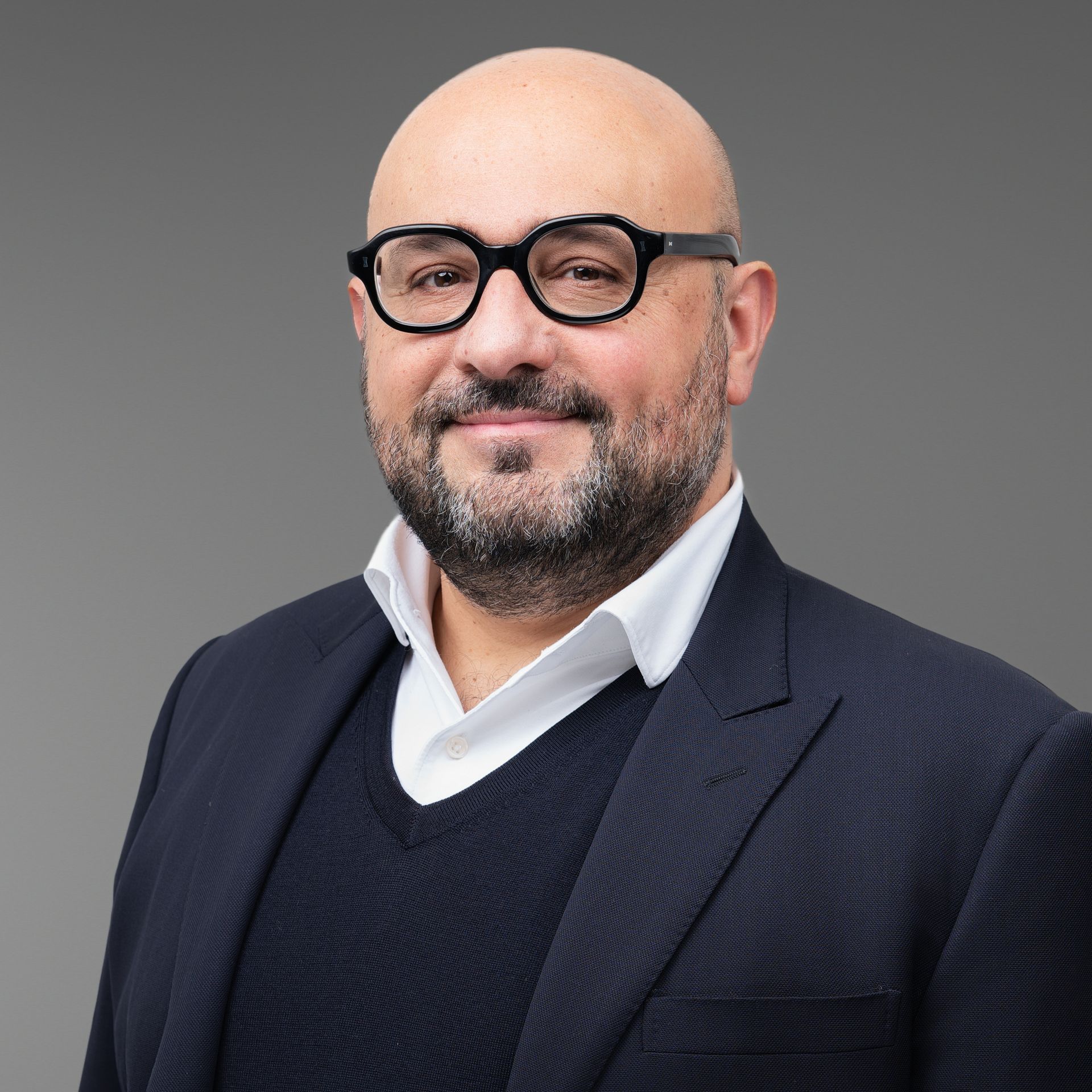 Man with glasses, suit jacket, and white shirt, smiling at the camera.