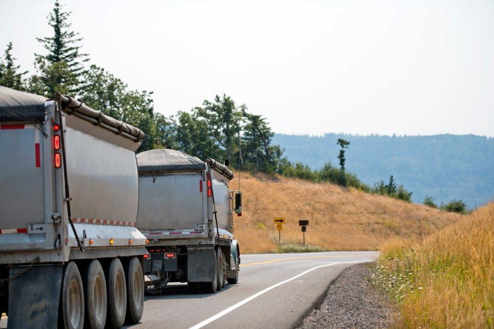 A Couple of Trucks Are Driving Down a Road — Jammach Earthmoving in Muswellbrook, NSW