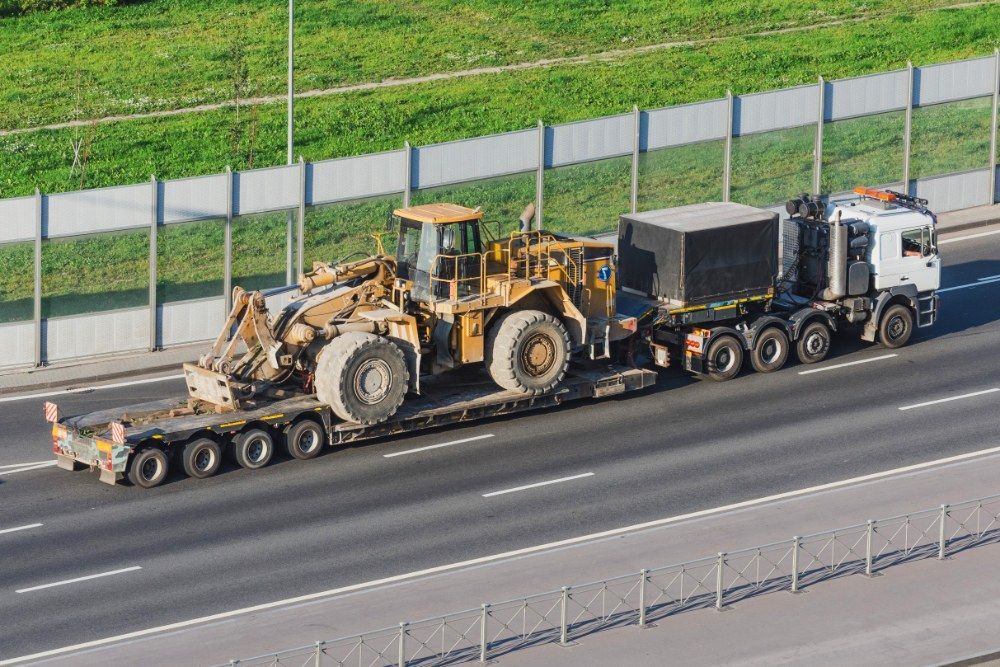 A Truck is Carrying a Bulldozer on a Trailer on a Highway — Jammach Earthmoving in Muswellbrook, NSW