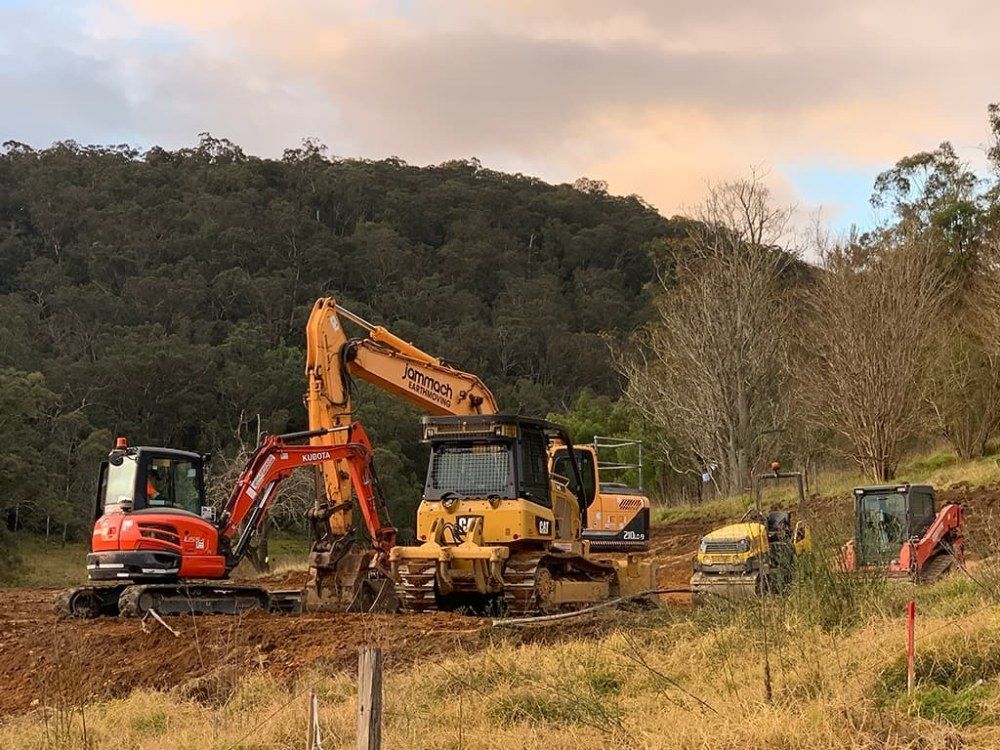 A Group of Construction Vehicles Are Working in a Field — Jammach Earthmoving in Maitland, NSW