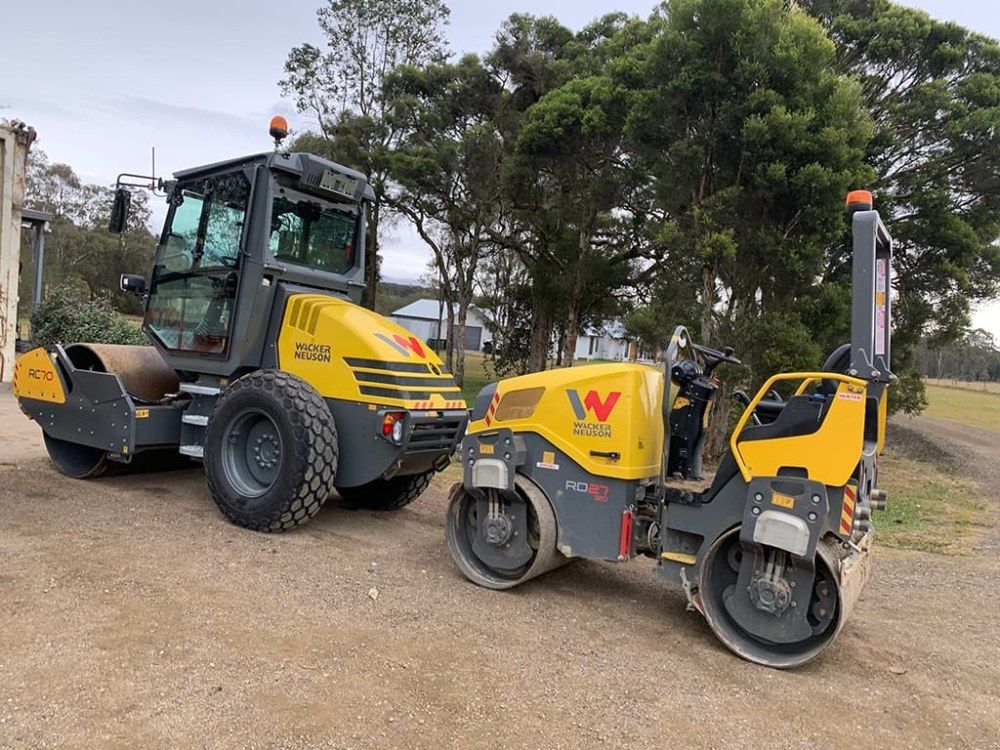 Two Construction Vehicles Are Parked Next to Each Other on a Dirt Road — Jammach Earthmoving in Maitland, NSW