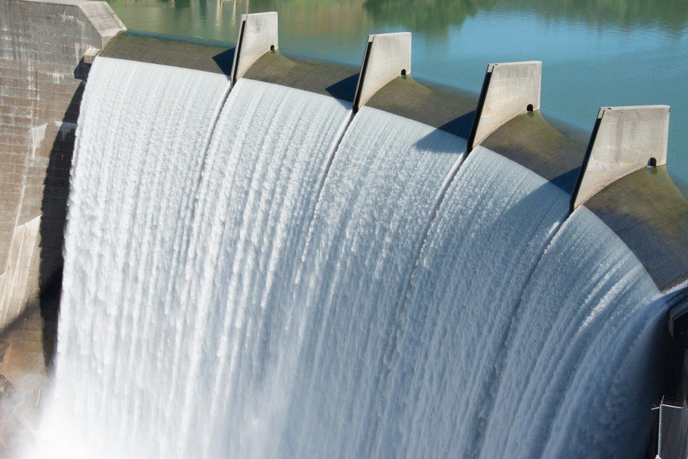 A Large Waterfall is Coming Down a Dam Into a Body of Water — Jammach Earthmoving in Muswellbrook, NSW