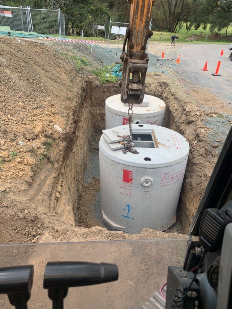 A Crane is Lifting Concrete Cylinders Into a Hole in the Ground — Jammach Earthmoving in Singleton, NSW