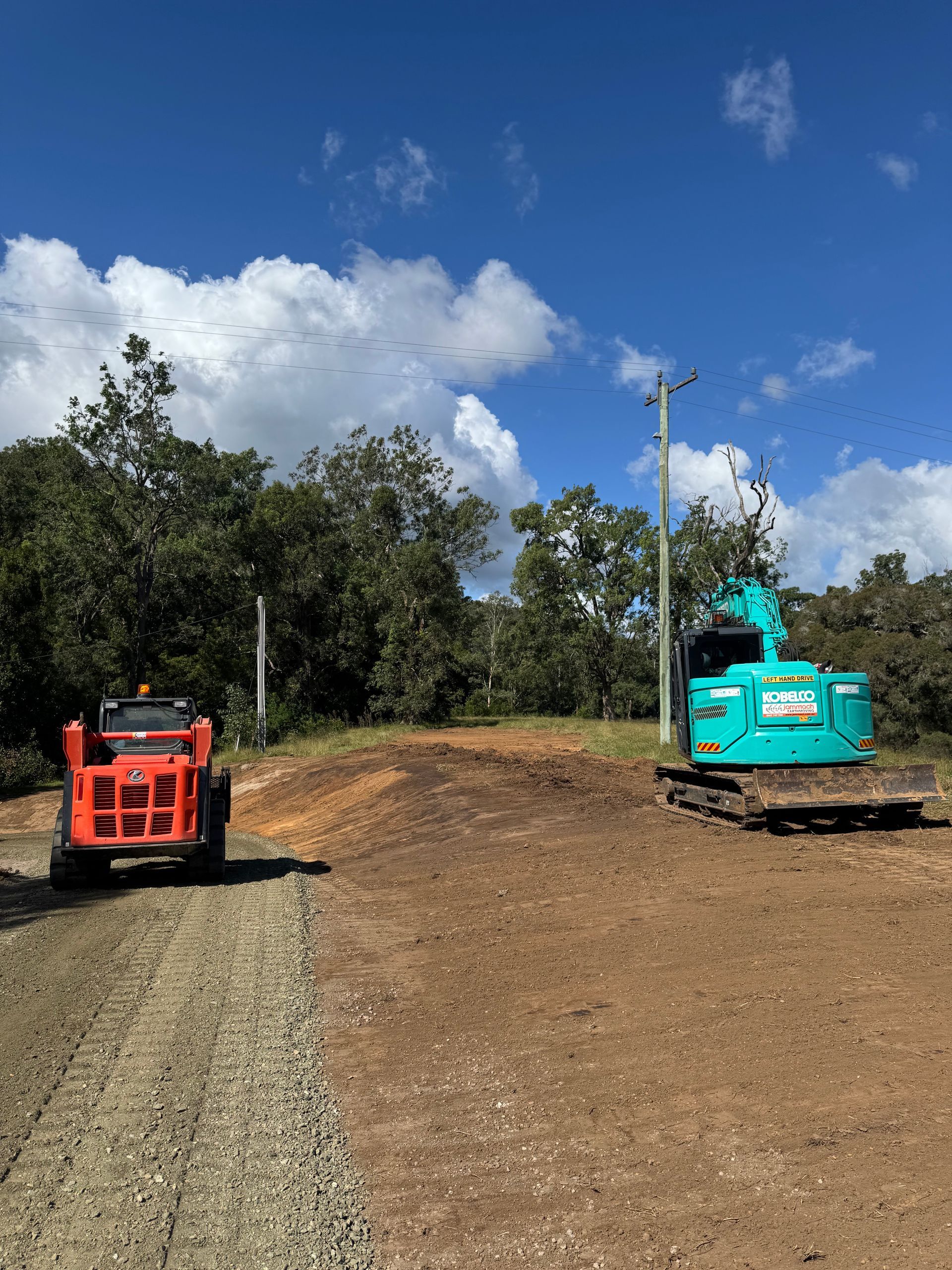 A Red Tractor and a Blue Excavator Are Parked Next to Each Other on a Dirt Road — Jammach Earthmoving in Nulkaba, NSW