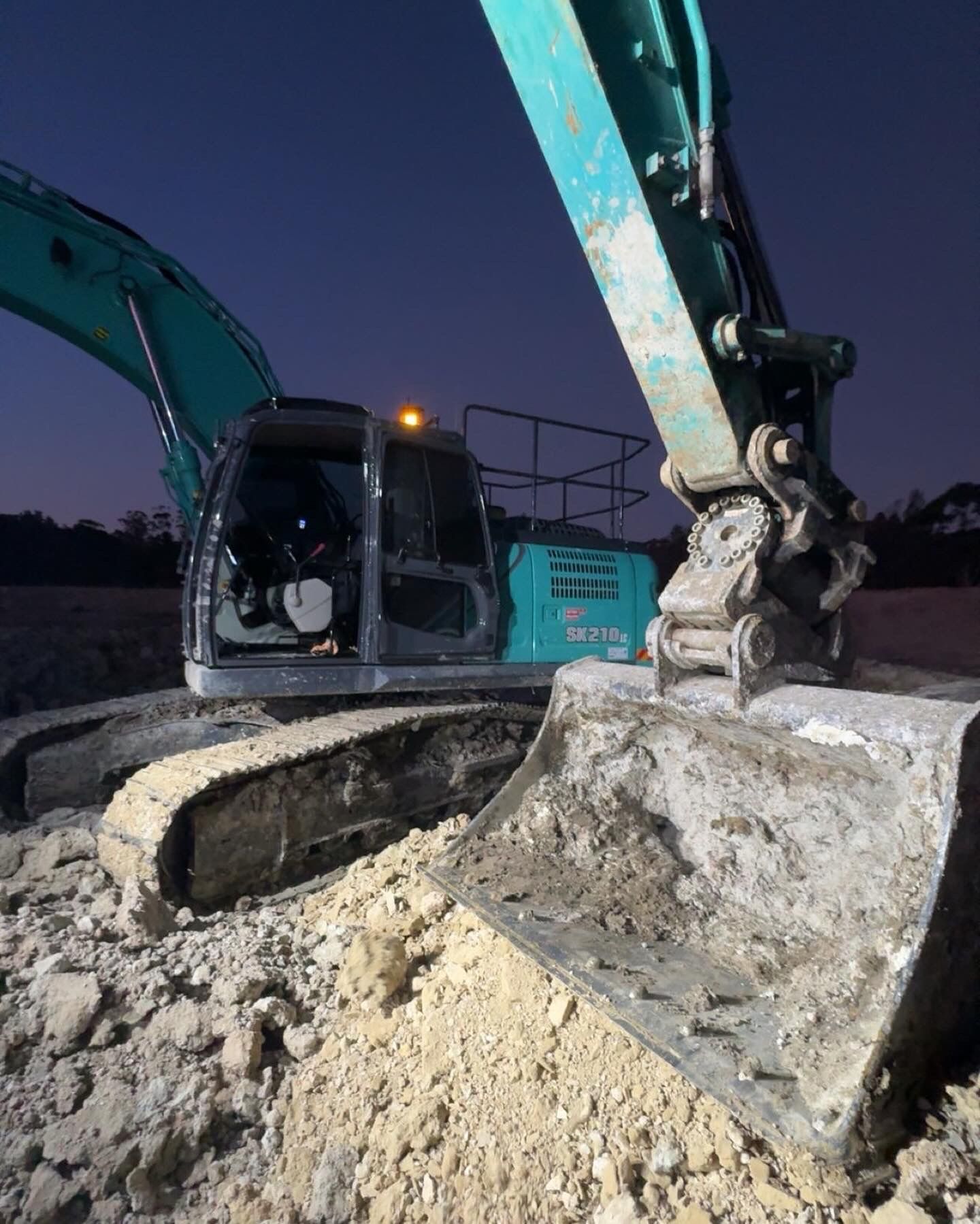 A Large Excavator is Digging a Hole in the Ground at Night — Jammach Earthmoving in Nulkaba, NSW