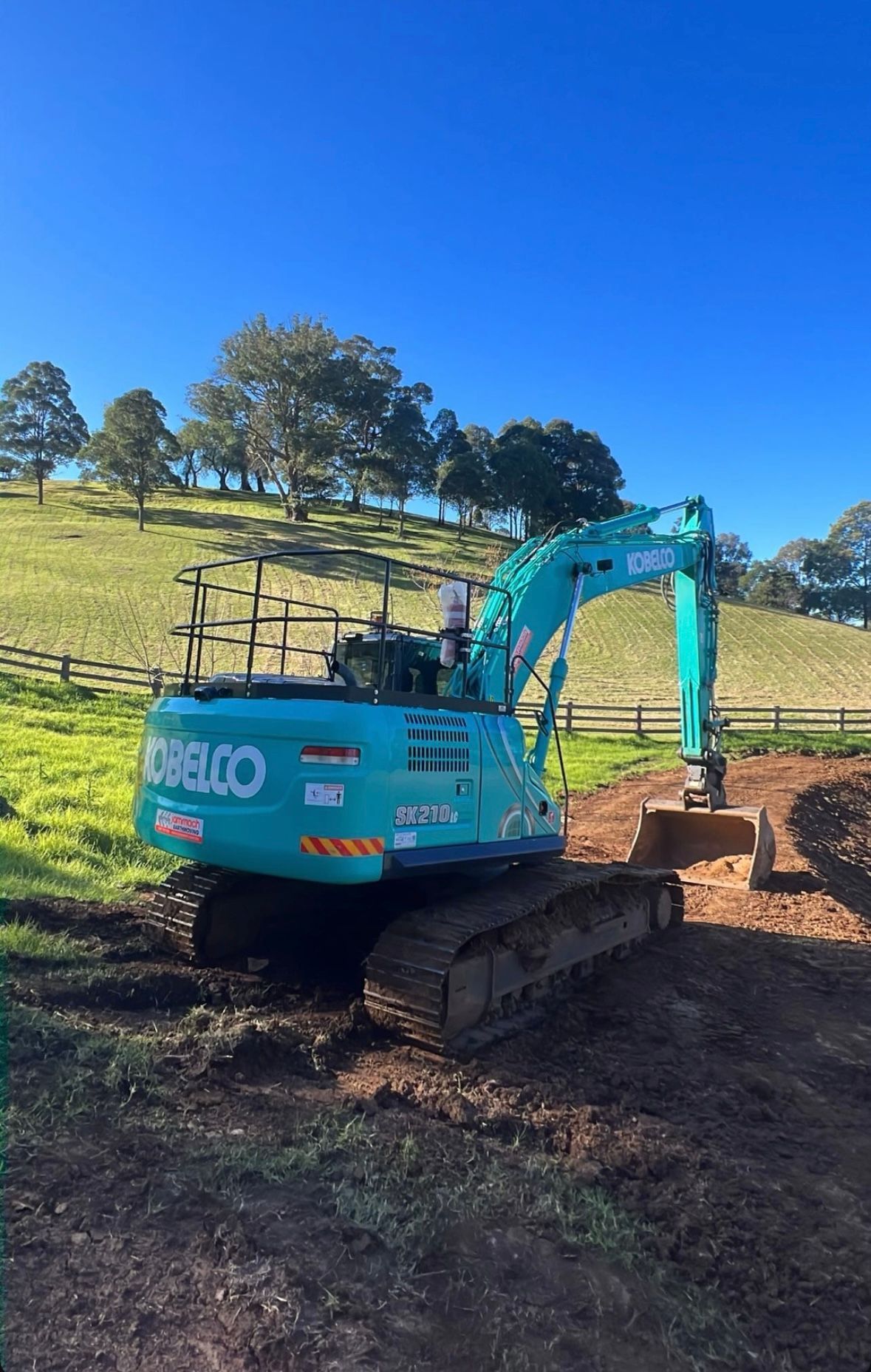A Blue Excavator is Parked on a Dirt Road in a Field — Jammach Earthmoving in Nulkaba, NSW