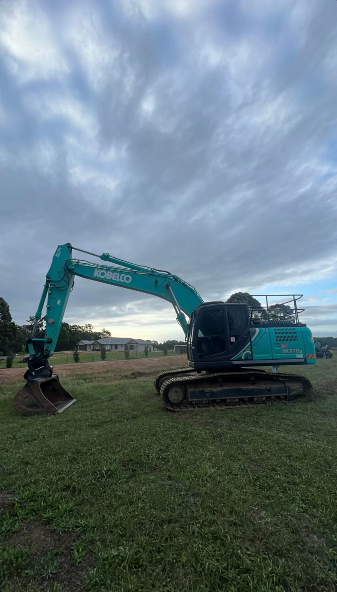 A Large Excavator is Sitting in the Middle of a Grassy Field — Jammach Earthmoving in Nulkaba, NSW