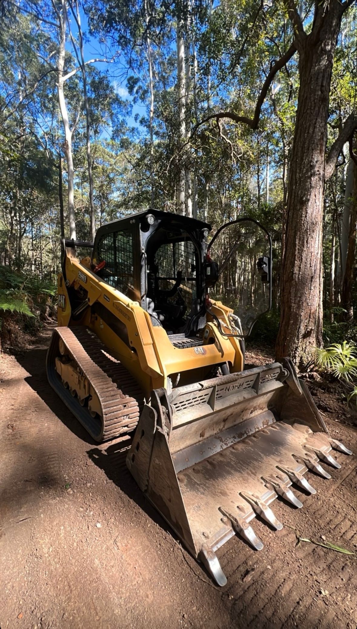 A Bulldozer is Parked on the Side of a Dirt Road in the Woods — Jammach Earthmoving in Nulkaba, NSW