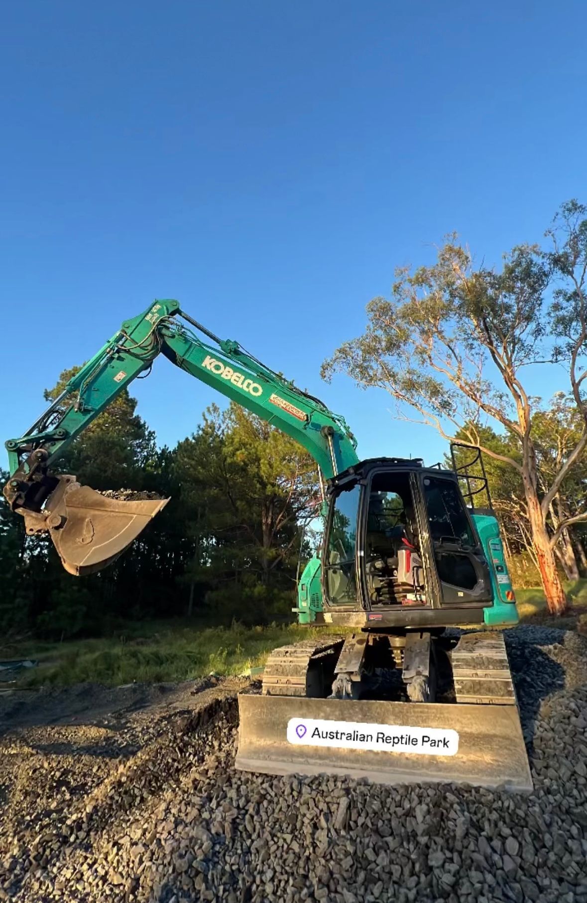 A Green Excavator is Sitting on Top of a Pile of Gravel — Jammach Earthmoving in Nulkaba, NSW
