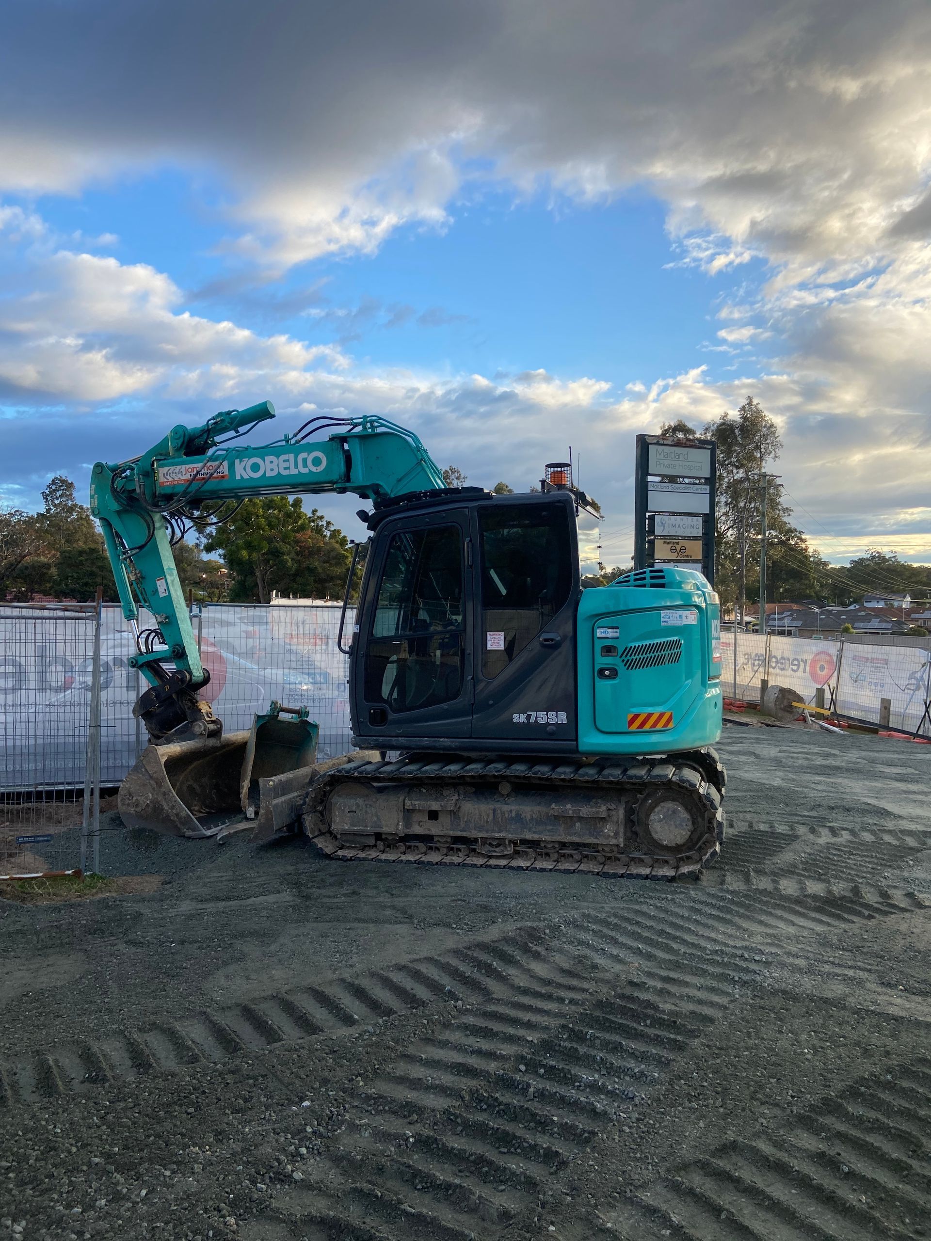 A Blue Excavator is Parked in a Gravel Lot on a Construction Site — Jammach Earthmoving in Nulkaba, NSW