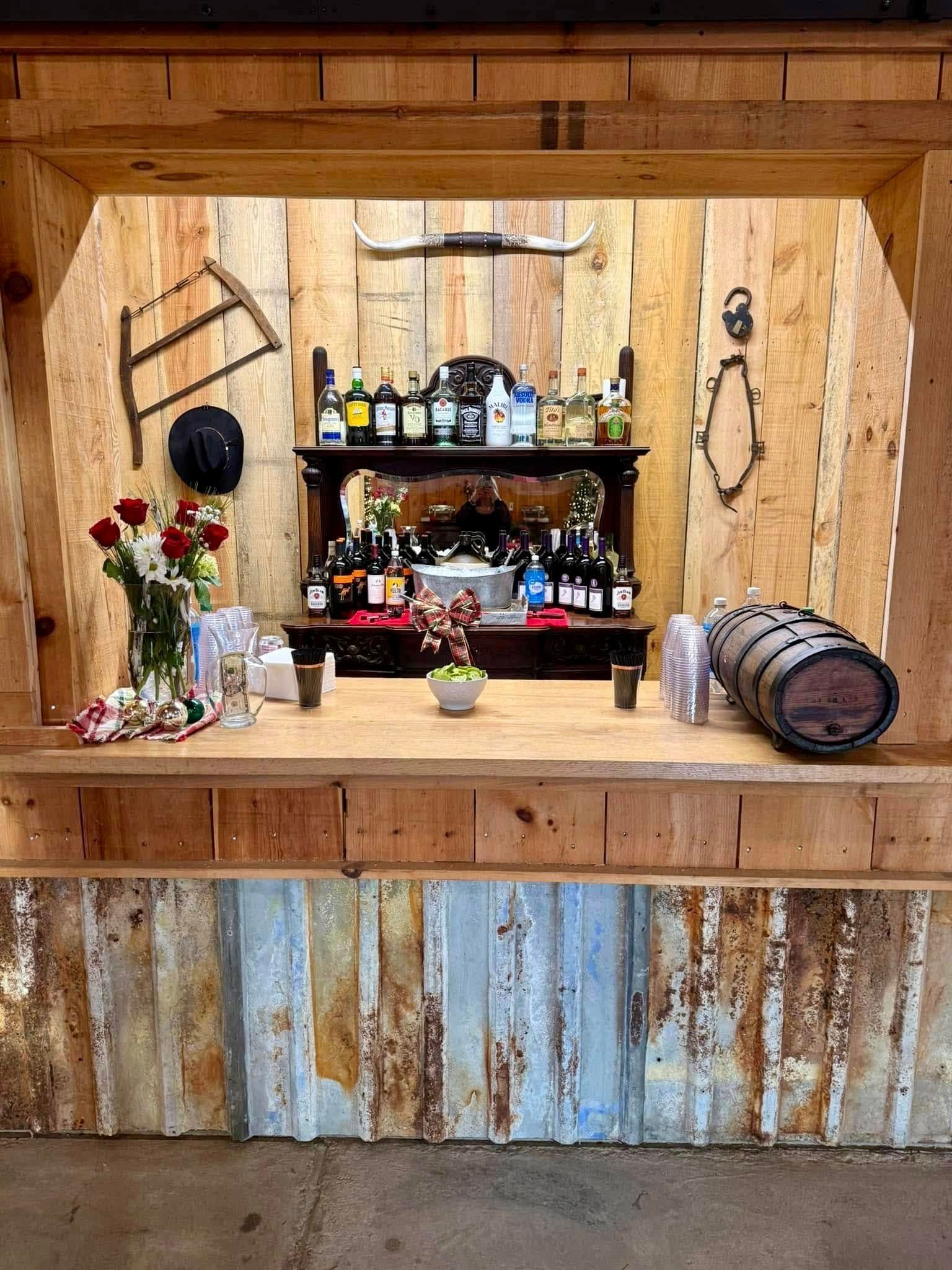Rustic wooden bar with liquor bottles, kegs, and decorations.