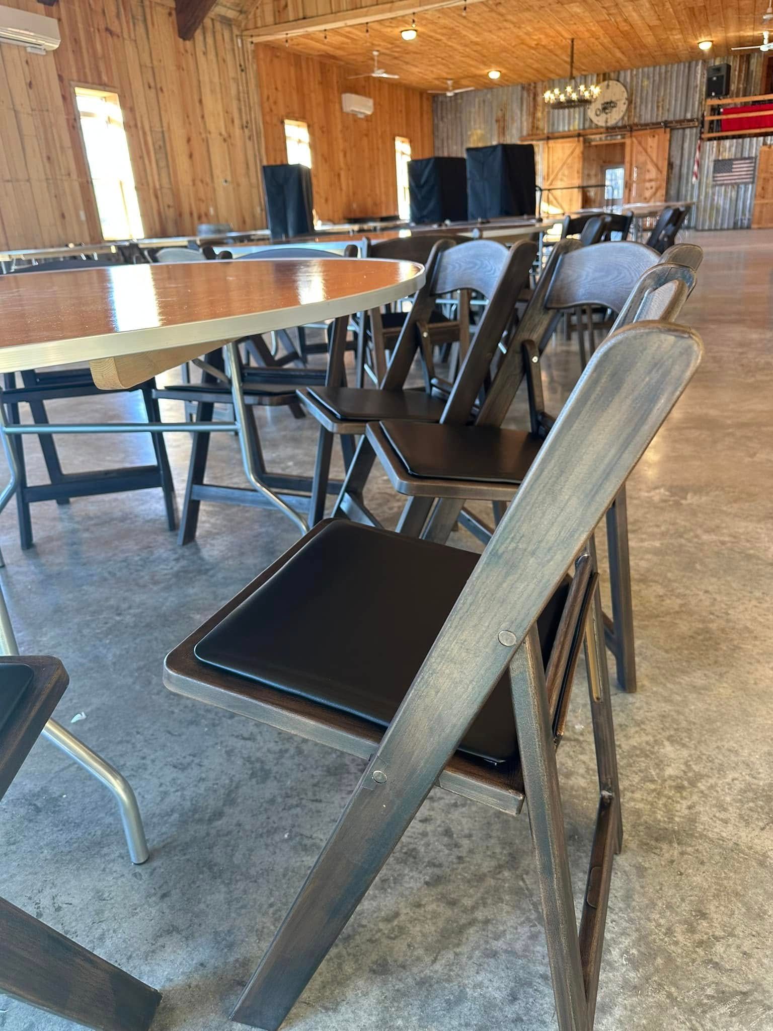 Wooden folding chairs and tables in a large room with concrete floors.