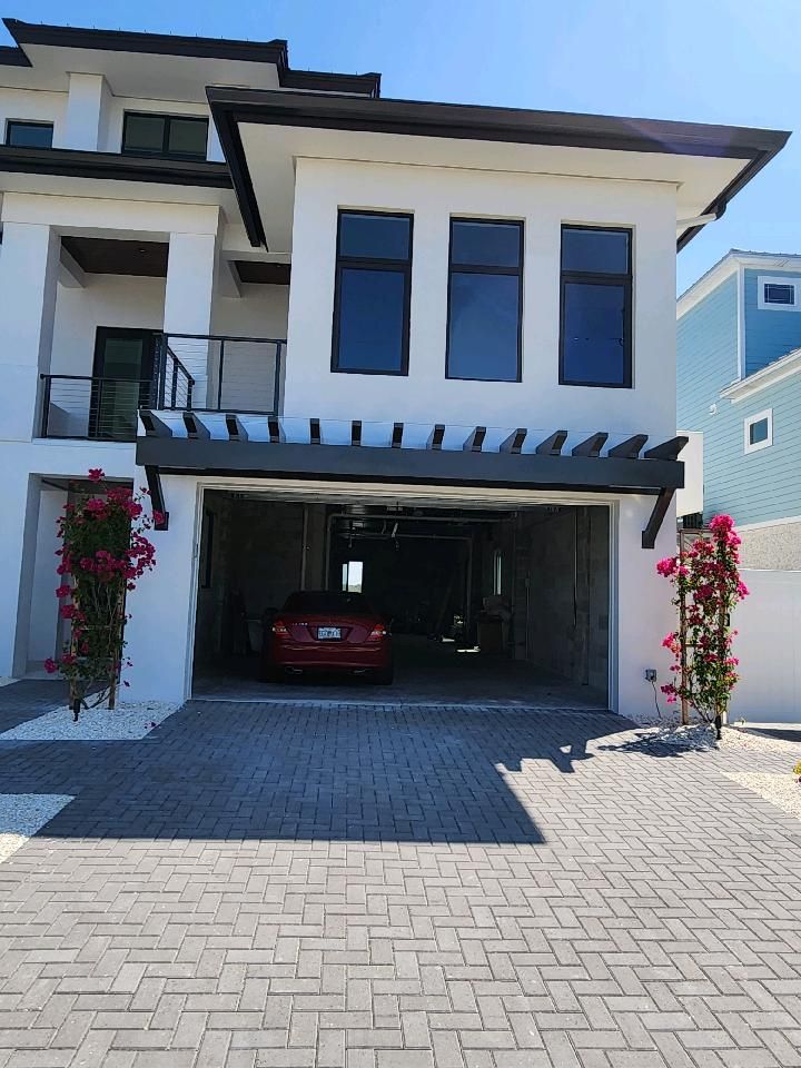 A white house with a red car parked in the garage.