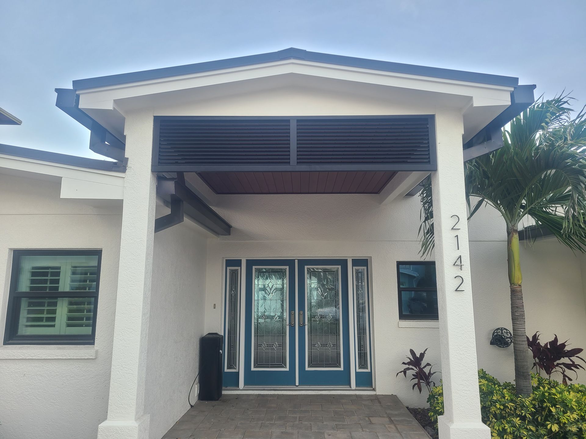 A white house with a blue door and a palm tree