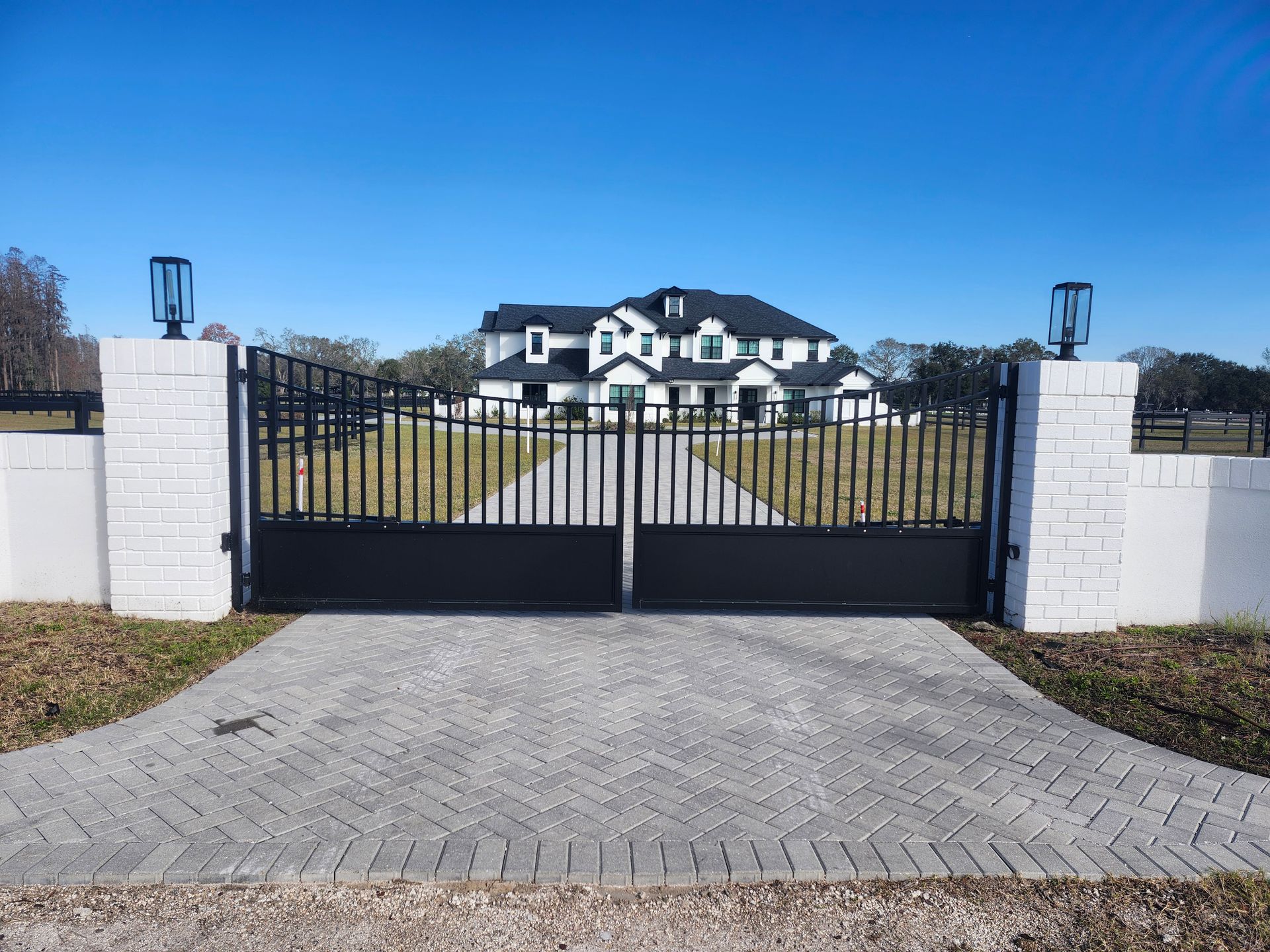A large white house is behind a black gate.