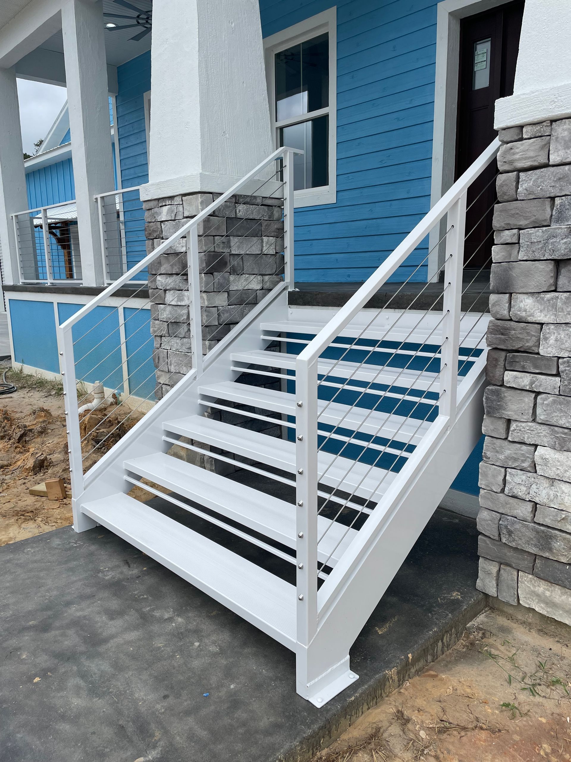 A white staircase leading up to a blue house