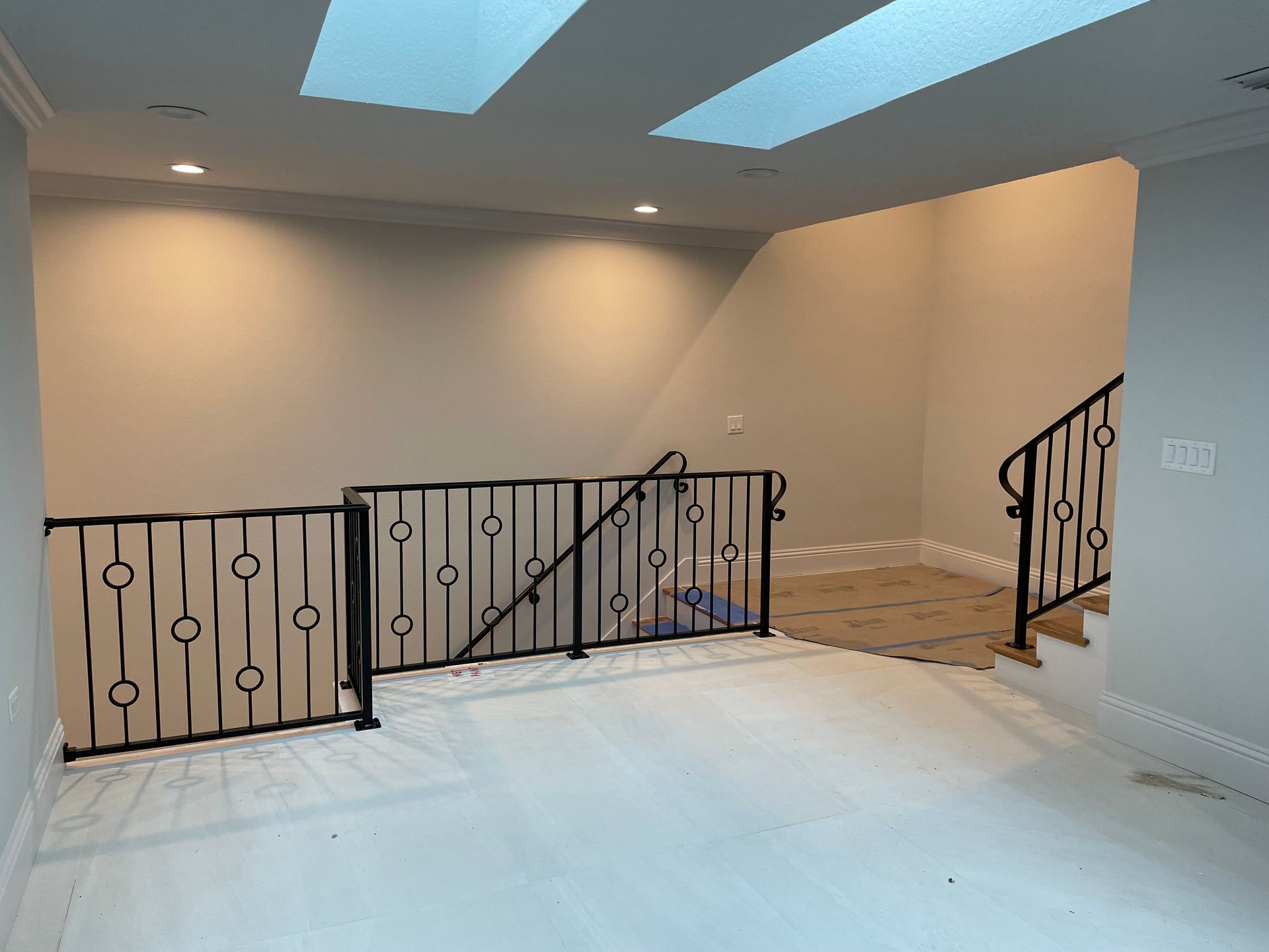 An empty room with a wrought iron railing and stairs.