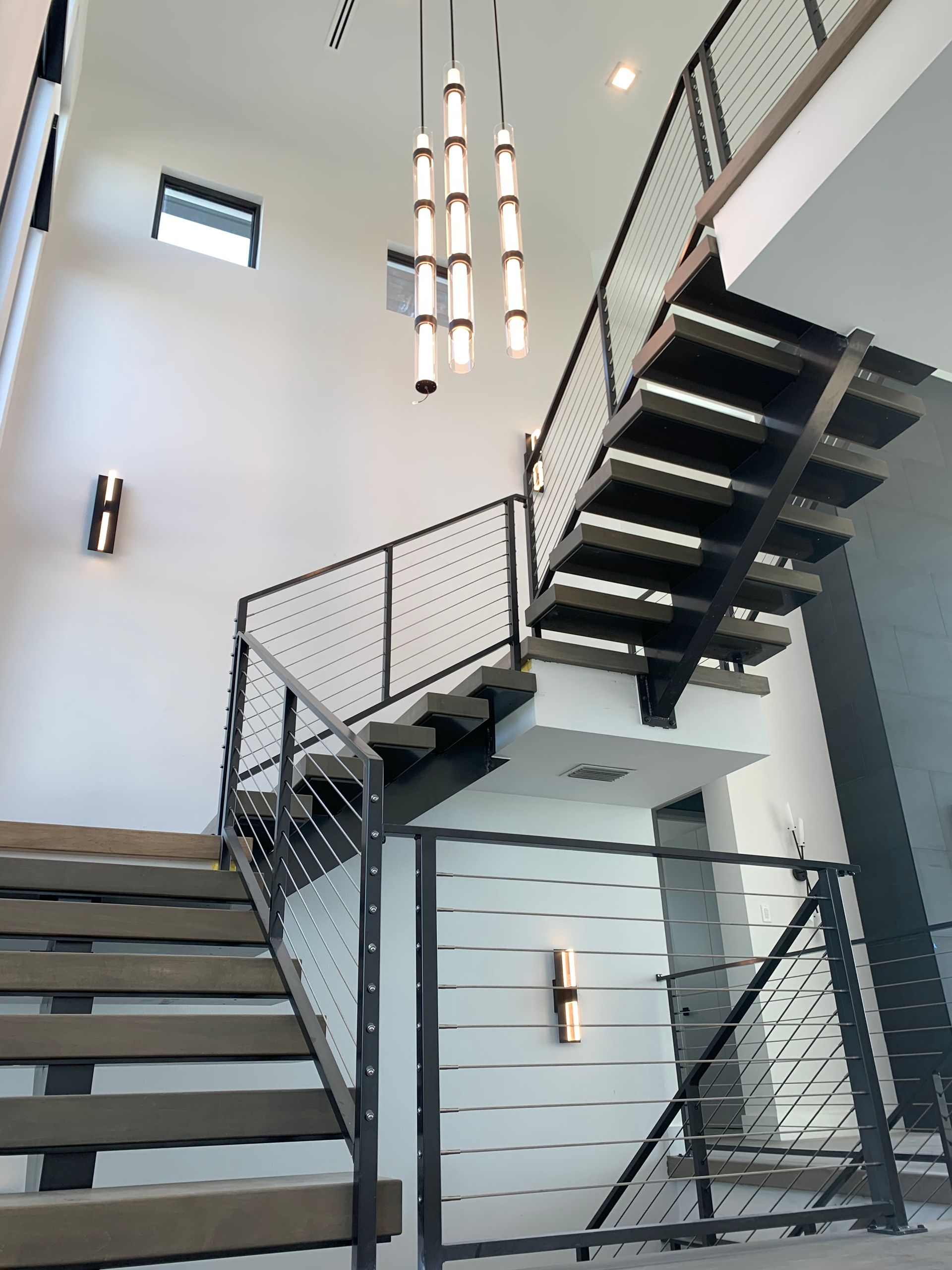 A staircase with a metal railing and a light hanging from the ceiling