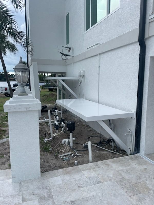 A white table is sitting on the side of a white building.