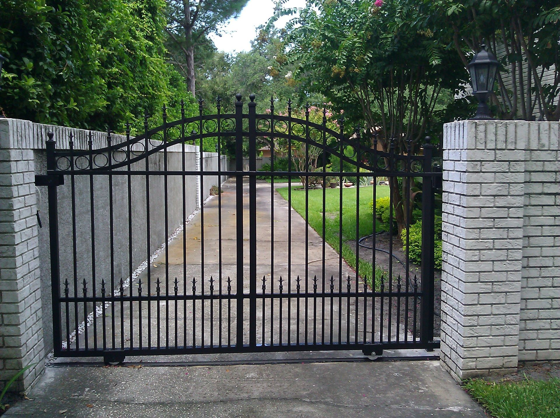 A black gate with a white brick wall behind it