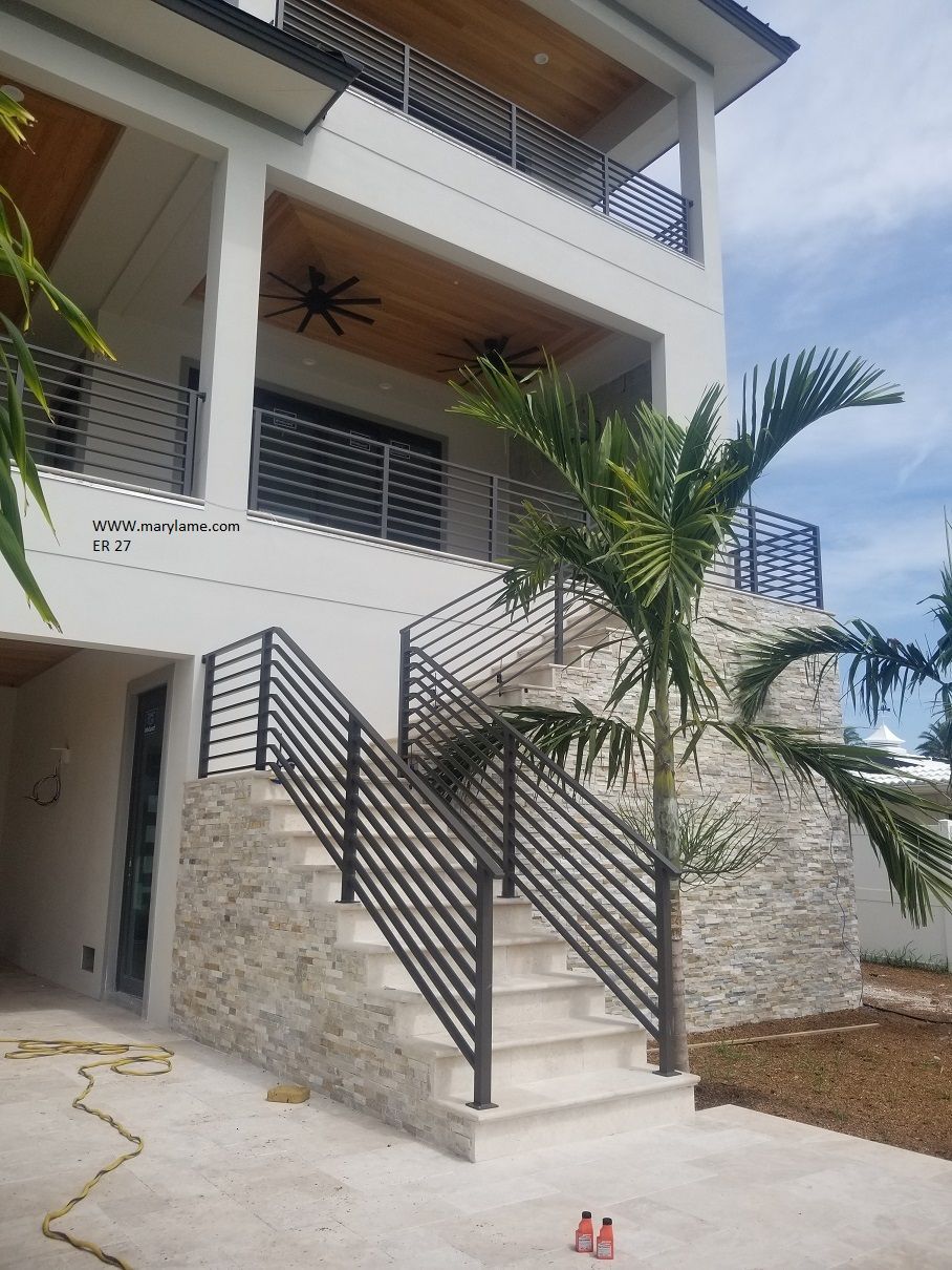 A large white house with stairs leading up to the second floor.