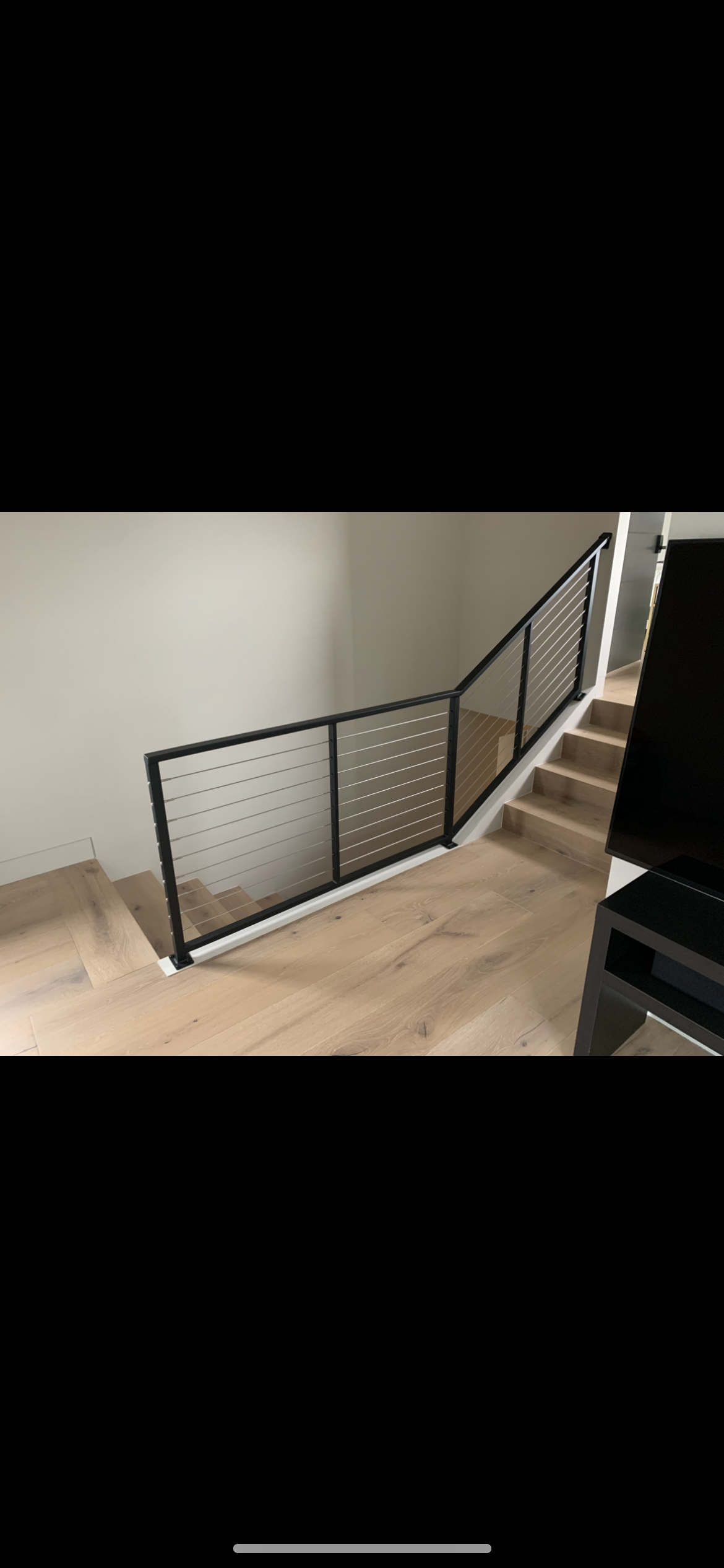 A staircase with a metal railing and a wooden floor in a living room.