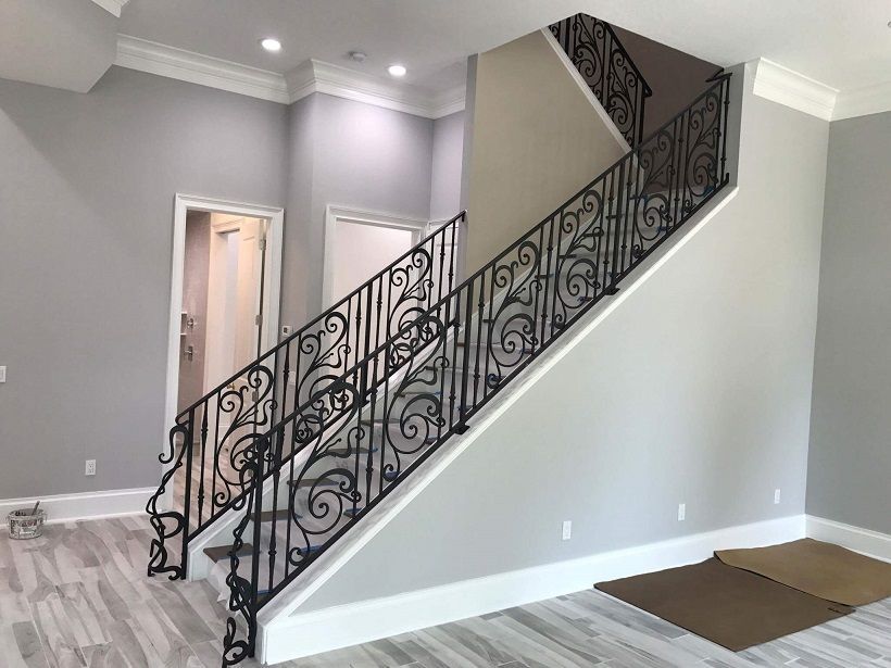 There is a staircase with a wrought iron railing in the middle of the room.