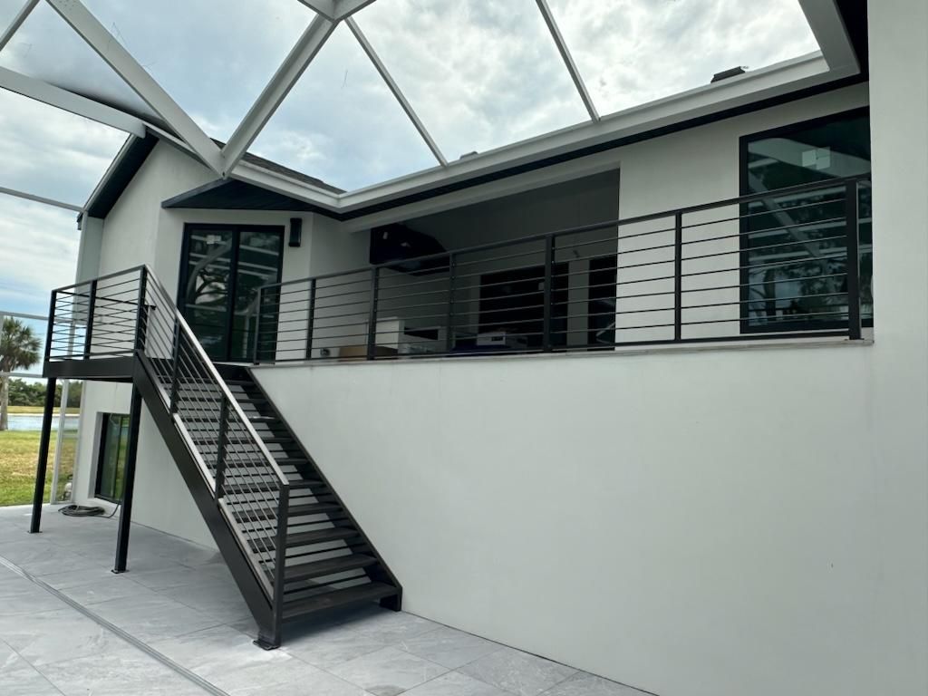 A white house with stairs leading up to a balcony.
