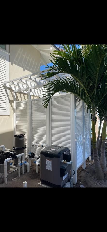 A white pergola is sitting next to a palm tree.